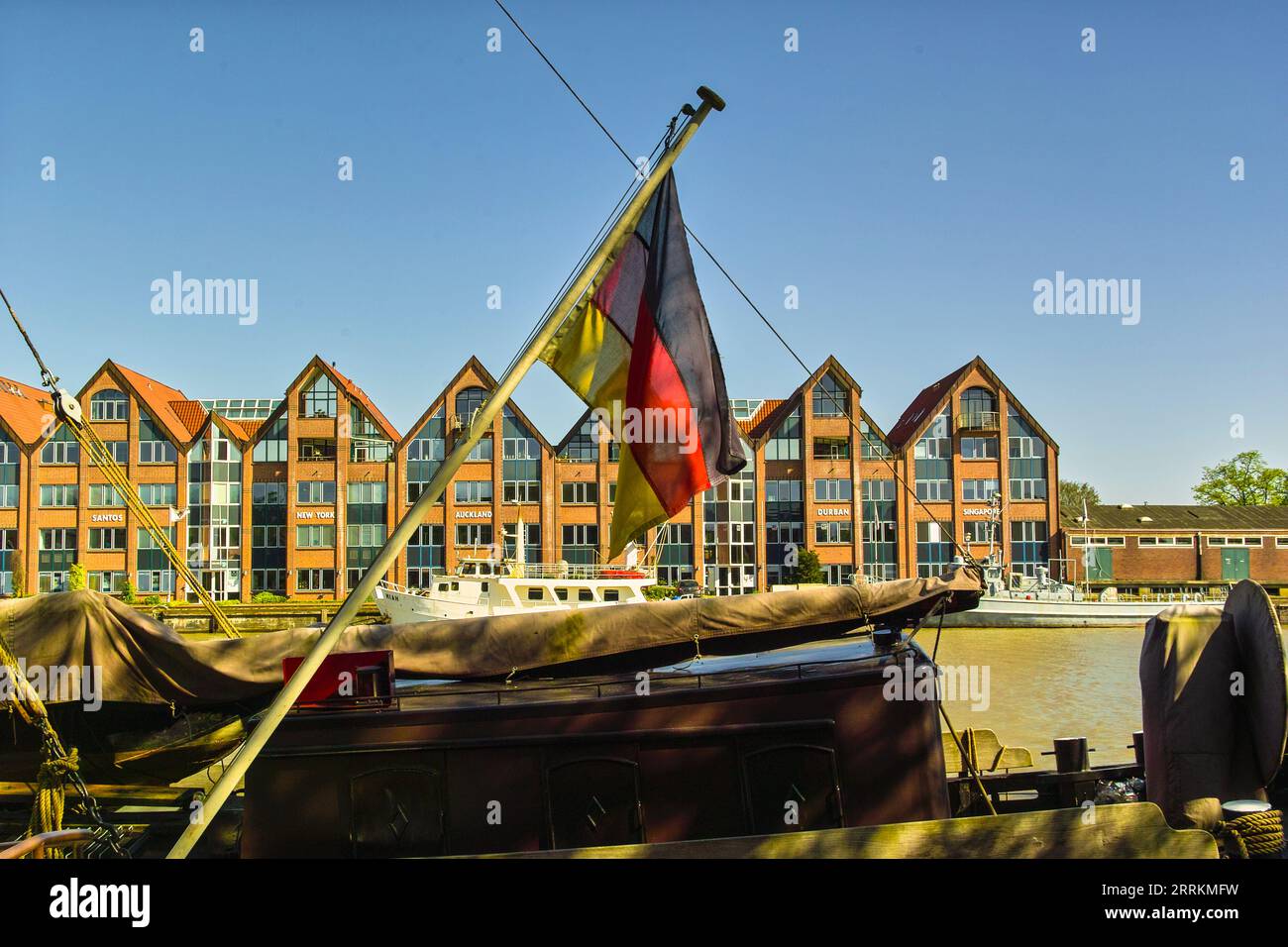 Deutsche Flagge am Heck eines Frachtschiffs im leer-Hafen, Schifffahrtsgebäude im Hintergrund Stockfoto