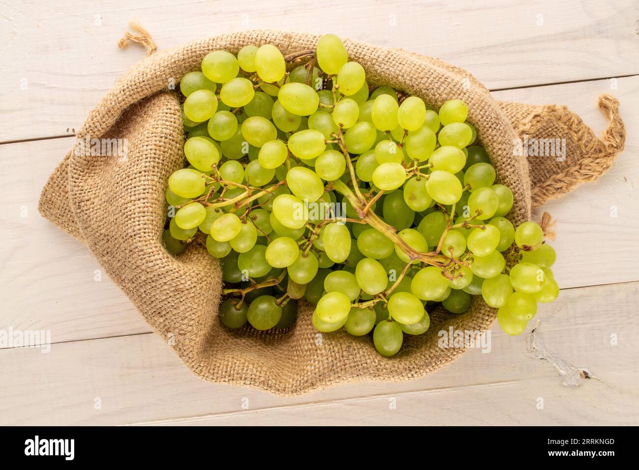Süße Bio-Trauben in einem Jutesack auf einem Holztisch, Makro, Draufsicht. Stockfoto