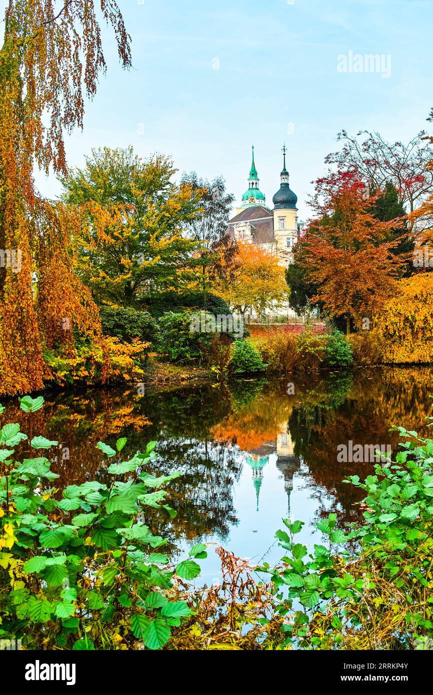 Der Herbst ist eine bunte Jahreszeit im Oldenburger Schlossgarten, einem Arboretumpark mitten in der Stadt. Die Türme der Burg sind im Hintergrund zu sehen. Stockfoto