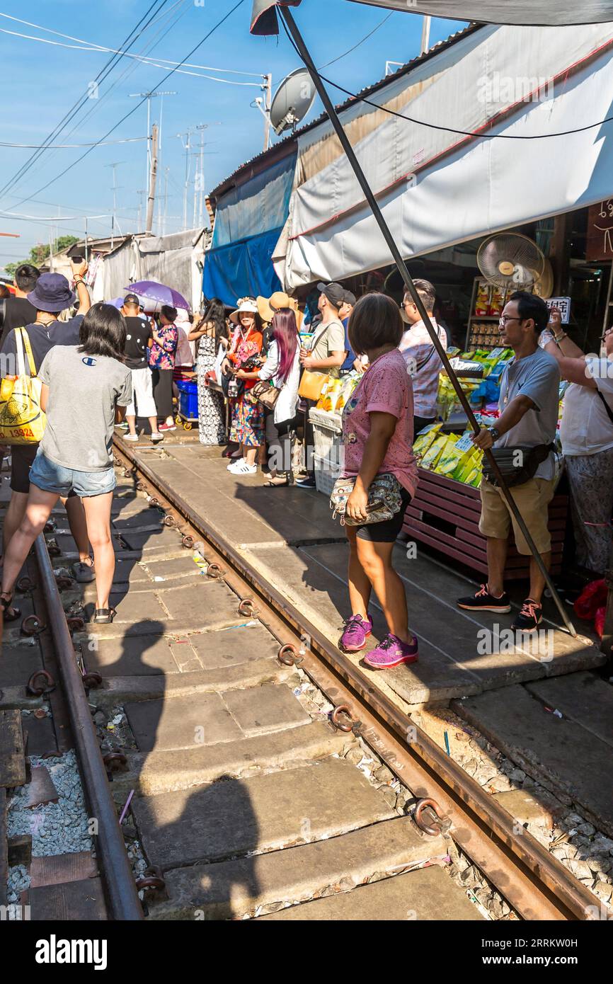 Touristen, die im Zug warten, Essen auf der Schiene verkaufen, Maeklong Railway Market, Talad Rom Hub Railway Market, in der Nähe von Bangkok, Samut Songkhram, Thailand, Asien Stockfoto