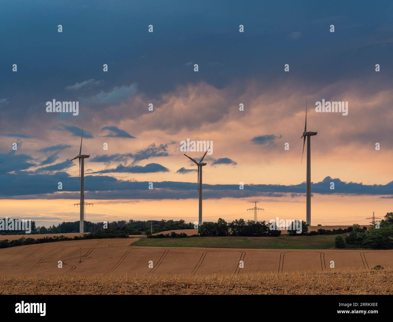 Windturbinen in Thüringen mit abfahrendem Gewitter im Sonnenuntergang. Stockfoto