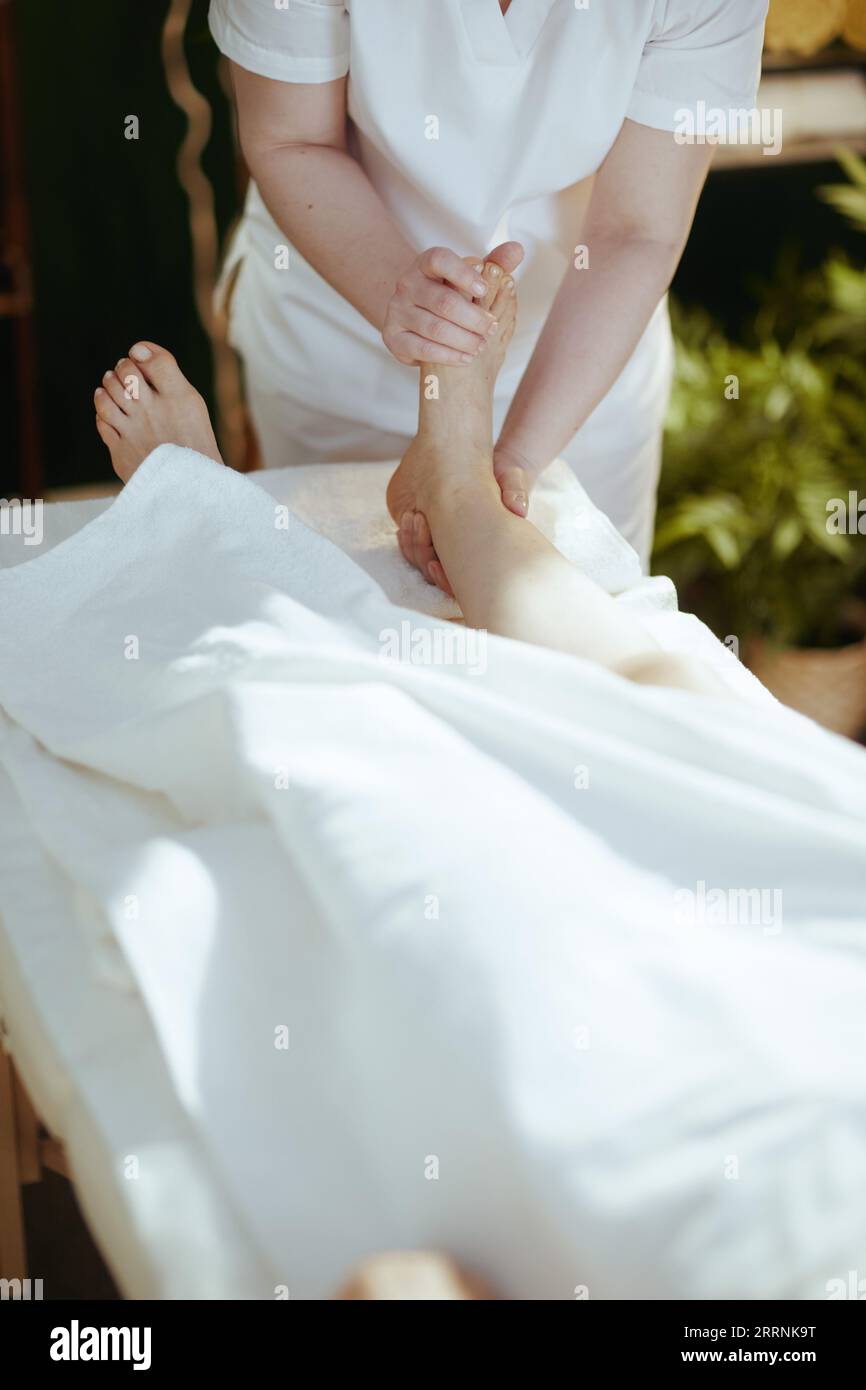 Gesundheitszeit. Nahaufnahme eines Massagetherapeuten im Massageschrank, der die Gäste mit dem Fuß auf dem Massagetisch massiert. Stockfoto