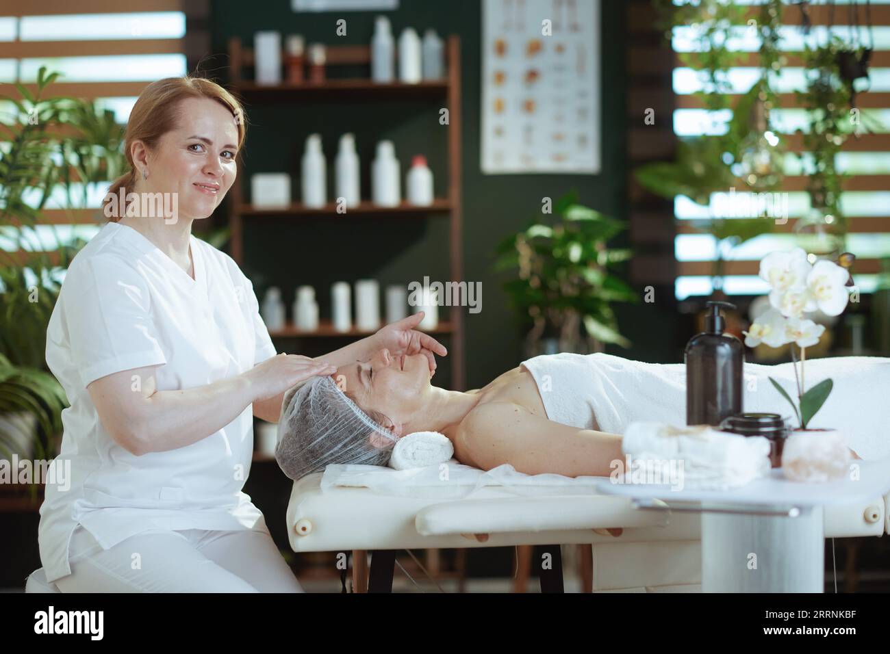 Gesundheitszeit. Massagetherapeut im Spa-Salon, der die Gäste mit dem Gesicht auf dem Massagetisch massiert. Stockfoto