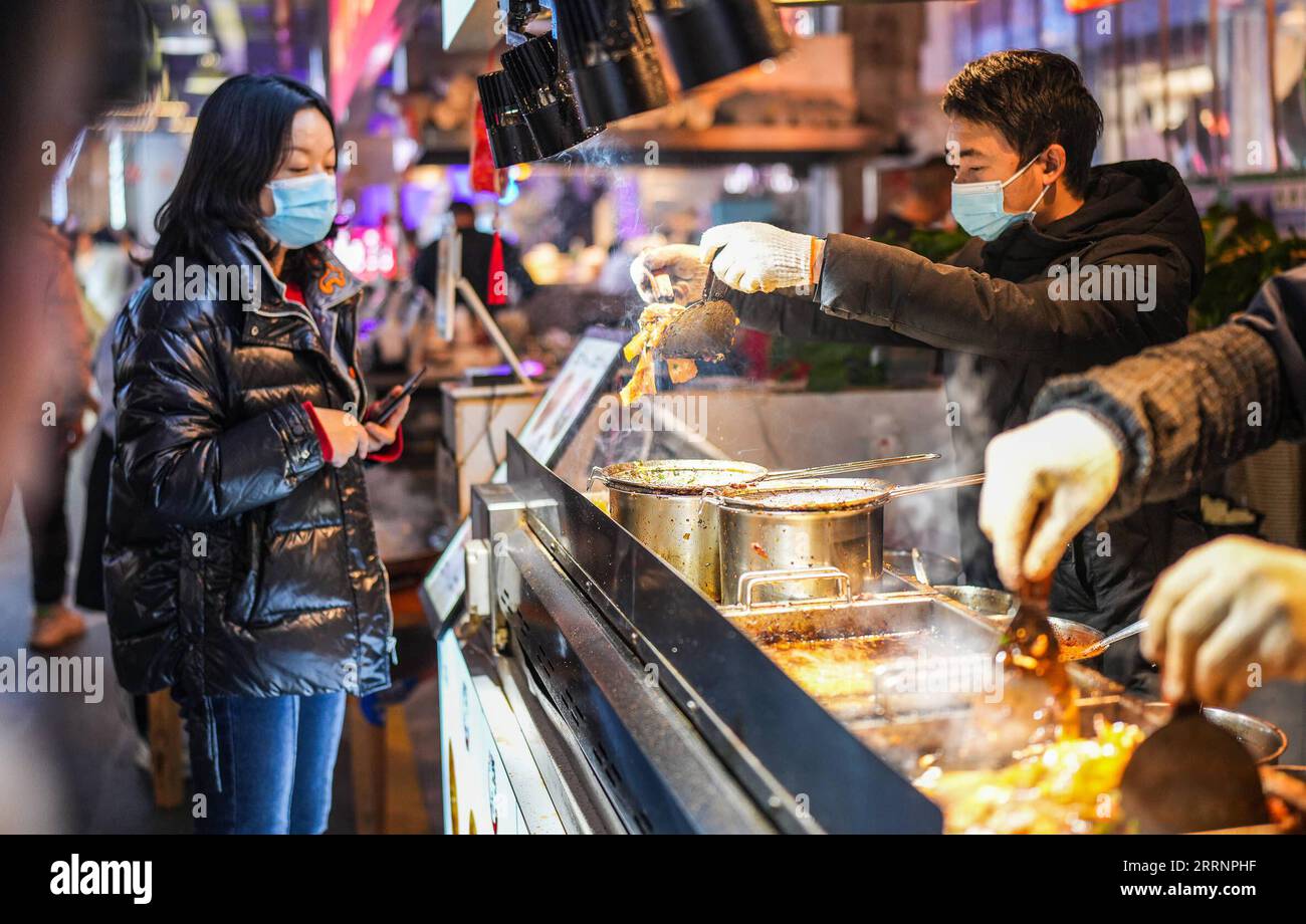 230124 -- GUIYANG, 24. Januar 2023 -- Ein Tourist kauft einen lokalen Snack im Nanming Bezirk von Guiyang, Südwestchinas Provinz Guizhou, 23. Januar 2023. Die Menschen genießen während der Frühlingsfesttage verschiedene Arten von Küche in China. CHINA-SPRING FESTIVAL-CUISINE CN TaoxLiang PUBLICATIONxNOTxINxCHN Stockfoto