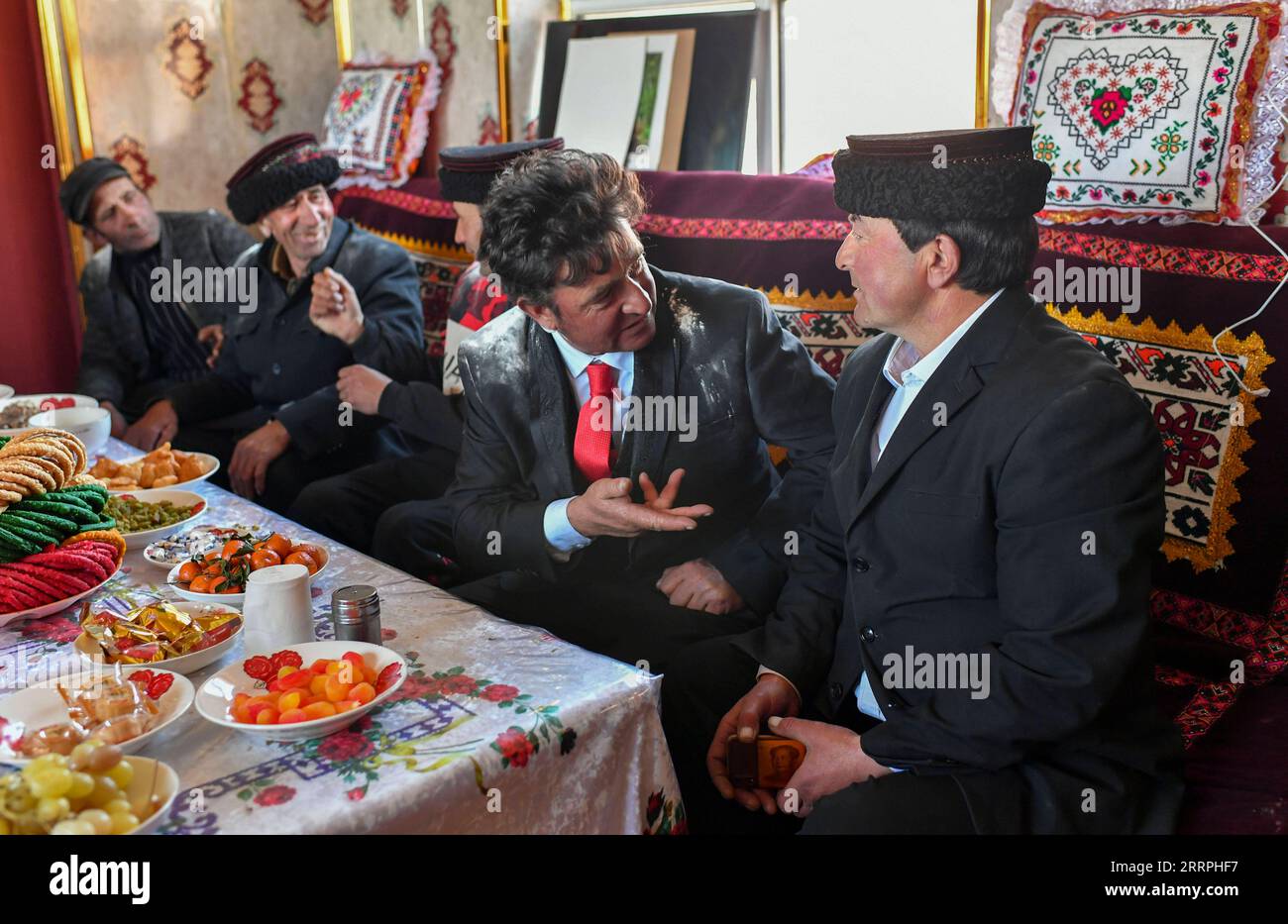 230325 -- TAXKORGAN, 25. März 2023 -- Duri Jarman 1st R spricht mit Freunden in seinem Haus im Aimin-Dorf des autonomen Bezirks Taxkorgan Tadschik im Nordwesten Chinas Xinjiang Uygur Autonomous Region, 21. März 2023. Das Leben des Hirten Duri Jarman ist eng mit zwei Orten verbunden: Dem Dorf Ak toga Langar, das tief in den Bergen des autonomen Bezirks Taxkorgan Tadschik liegt, und dem Dorf Aimin, das sich in der Nähe des Verwaltungssitzes befindet. Duri, heute 52 Jahre alt, lebte 47 Jahre im Dorf Ak toga Langar. Im Winter 2018 profitierte seine Familie von der Umsiedlungspolitik zur Armutsbekämpfung und -Regelung Stockfoto