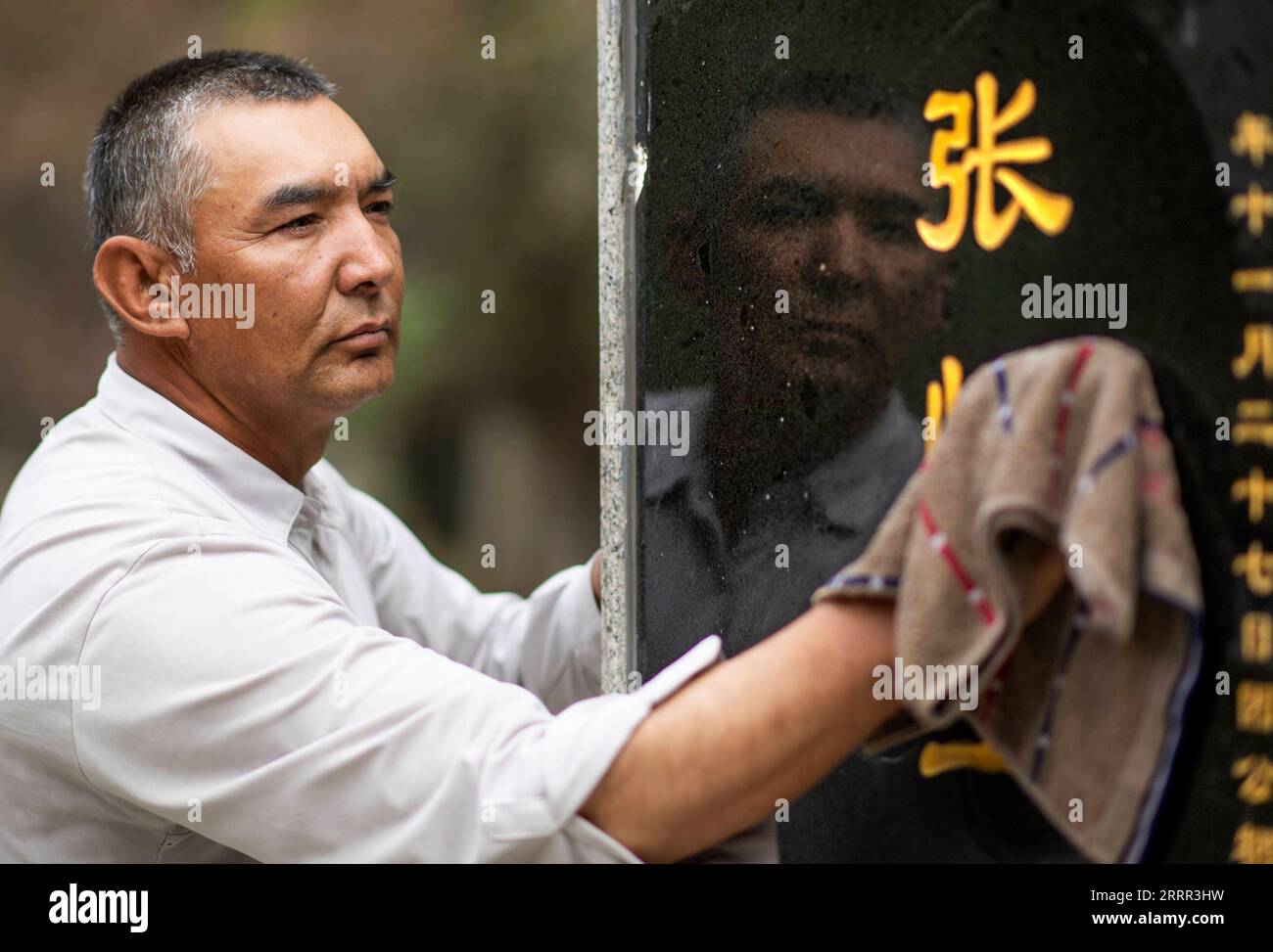 230430 -- YECHENG, 30. April 2023 -- Eniwar Emer wischt einen Grabstein auf dem Yecheng Märtyrerfriedhof in Yecheng, Nordwestchinas autonome Region Xinjiang Uygur, 16. April 2023. Jedes Jahr im April blühen Blumen auf dem Yecheng Martyrs Cemetery in der autonomen Region Xinjiang Uygur im Nordwesten Chinas, wo 233 Märtyrer begraben wurden. Ich werde mich gut um den Friedhof kümmern, sagte der 53-jährige Eniwar Emer vor dem Grabstein seines Vaters. Eniwar ist ein Pfleger der zweiten Generation auf dem Yecheng Martyrs Cemetery, der den Spuren seines Vaters Emer YIT folgte, der dort von 1970 bis 1945 die Gräber gepflegt hatte Stockfoto