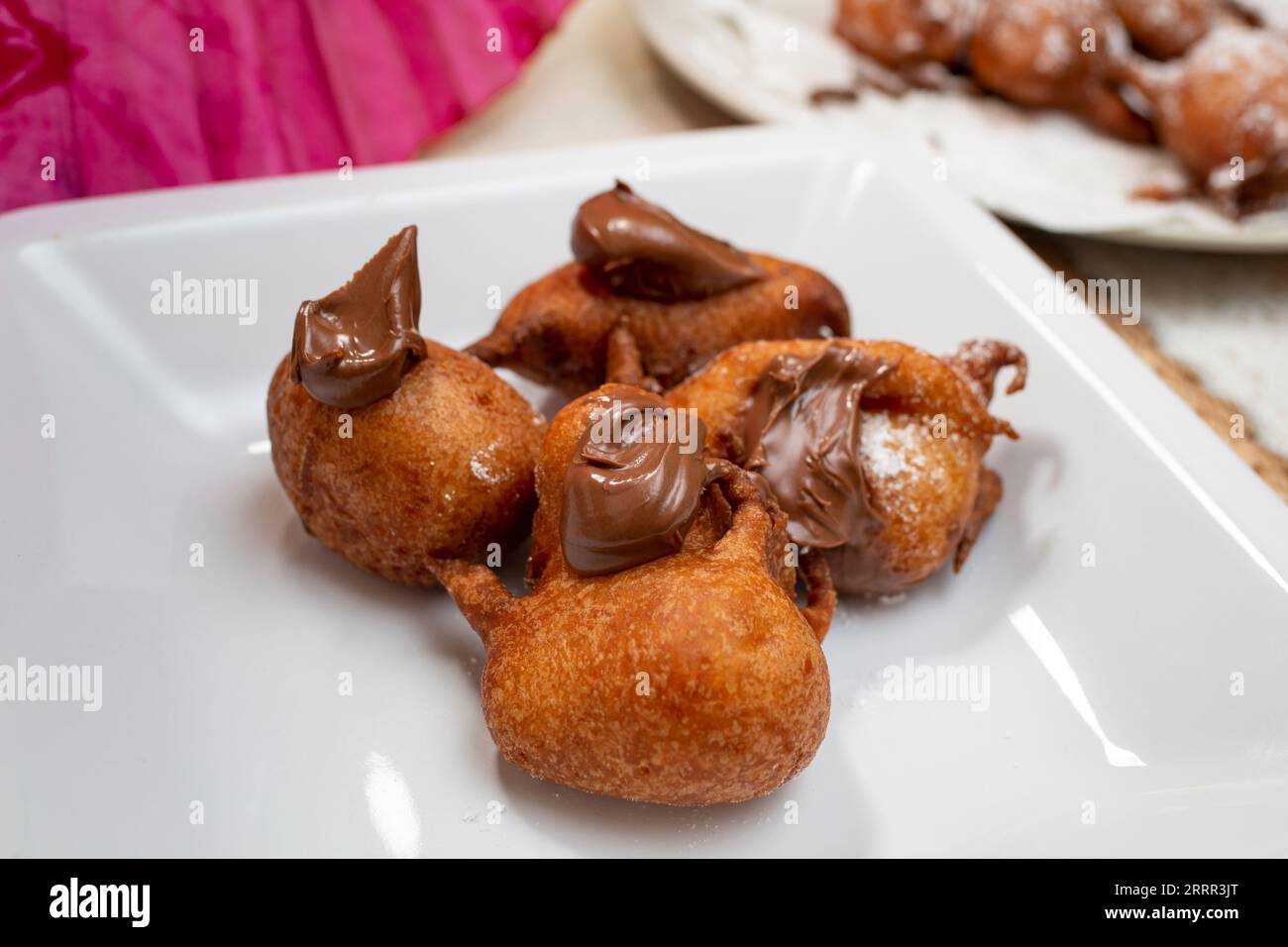 Braune unregelmäßige Donuts auf einer quadratischen weißen Keramik spät mit Schokoladencreme Stockfoto