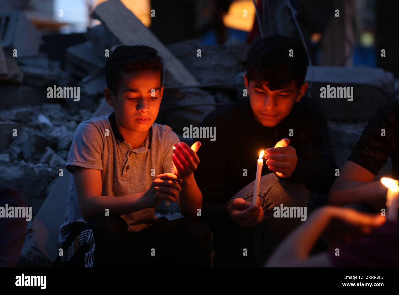 230515 -- GAZA, 15. Mai 2023 -- palästinensische Kinder halten Kerzen, während sie auf den Ruinen eines Hauses sitzen, das während der israelischen Luftangriffe im südlichen Gazastreifen Rafah am 14. Mai 2023 zerstört wurde. Die fünftägige Konfrontation begann, nachdem am Dienstag ein israelischer Luftangriff drei hochrangige PIJ-Führer im Gazastreifen getötet hatte. Während der Kämpfe startete Israel Hunderte von Luftangriffen, bei denen mindestens 33 Palästinenser getötet und mehr als 150 andere verletzt wurden, so das Gesundheitsministerium in Gaza. Foto von /Xinhua MIDEAST-GAZA-RAFAH-KERZEN AUF RUINEN KhaledxOmar PUBLICATIONxNOTxINxCHN Stockfoto