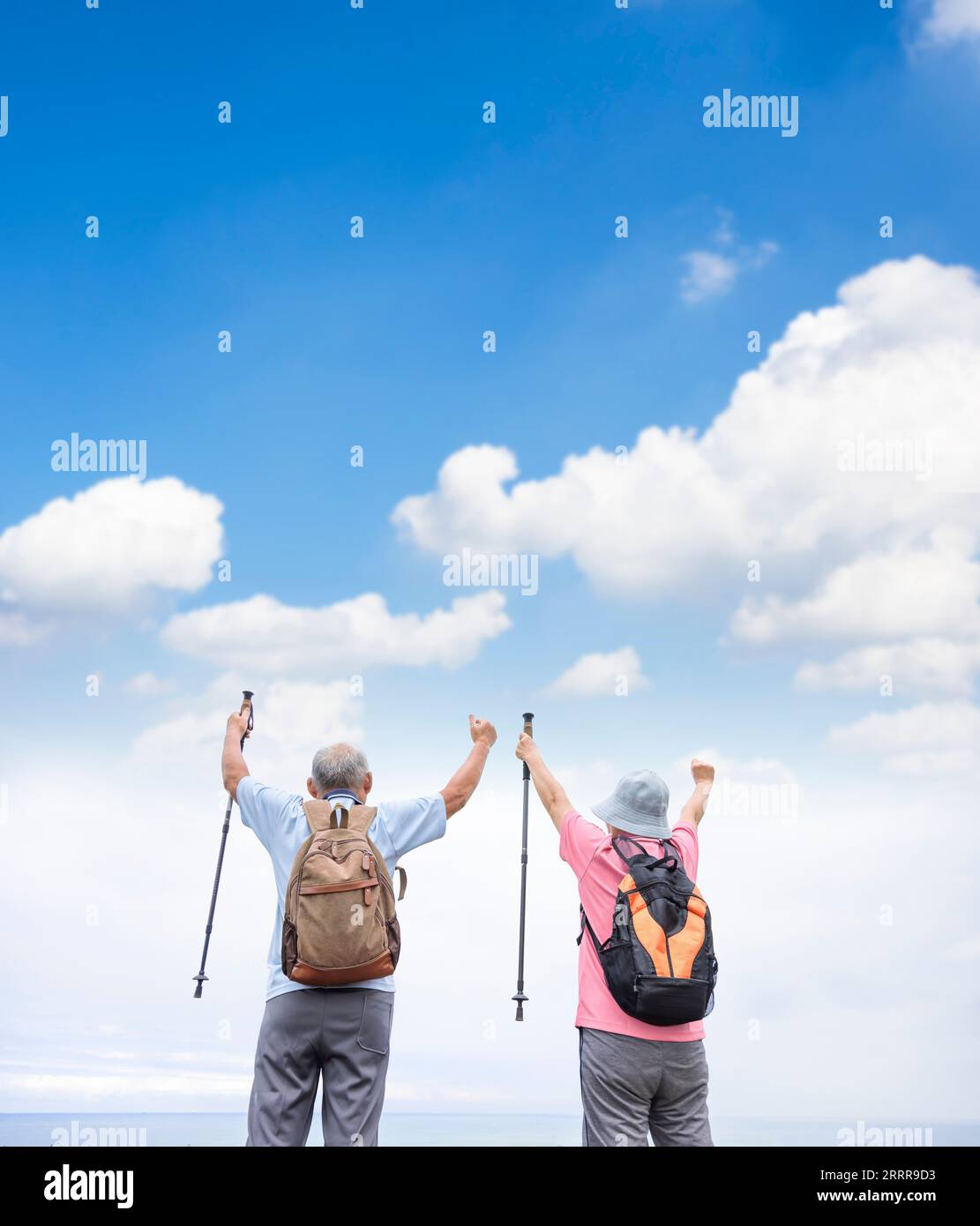 Rückansicht des glücklichen Seniorenpaares, das zusammen mit dem Wolkenhintergrund wandert Stockfoto