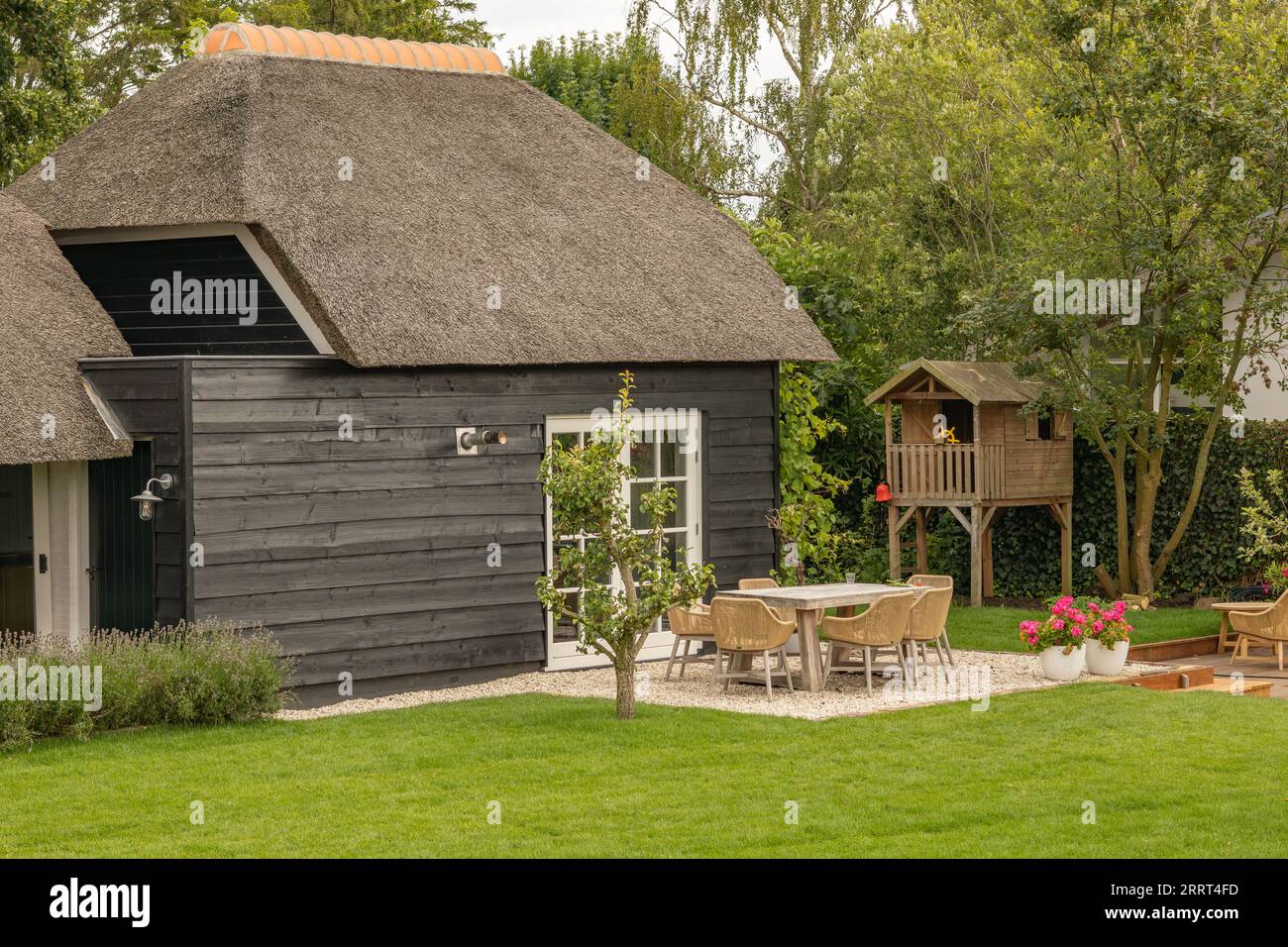 Holzhaus mit Strohdach und gepflegtem Garten Stockfoto