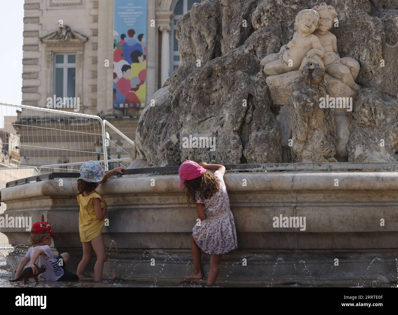 230720 -- MONTPELLIER, 20. Juli 2023 -- Kinder kühlen sich an einem Brunnen von drei Grazen auf dem Place de Comedie ab, da die höchste Temperatur in Montpellier, Südfrankreich, am 19. Juli 2023 38 Grad Celsius erreicht. Am Mittwoch wurden in ganz Europa Warnungen wegen extremer Hitze ausgegeben, da der beste Teil des Kontinents von der intensivsten Hitzewelle seit Beginn der Aufzeichnungen erfasst wurde. FRANCE-MONTPELLIER-HEATWAVE GaoxJing PUBLICATIONxNOTxINxCHN Stockfoto