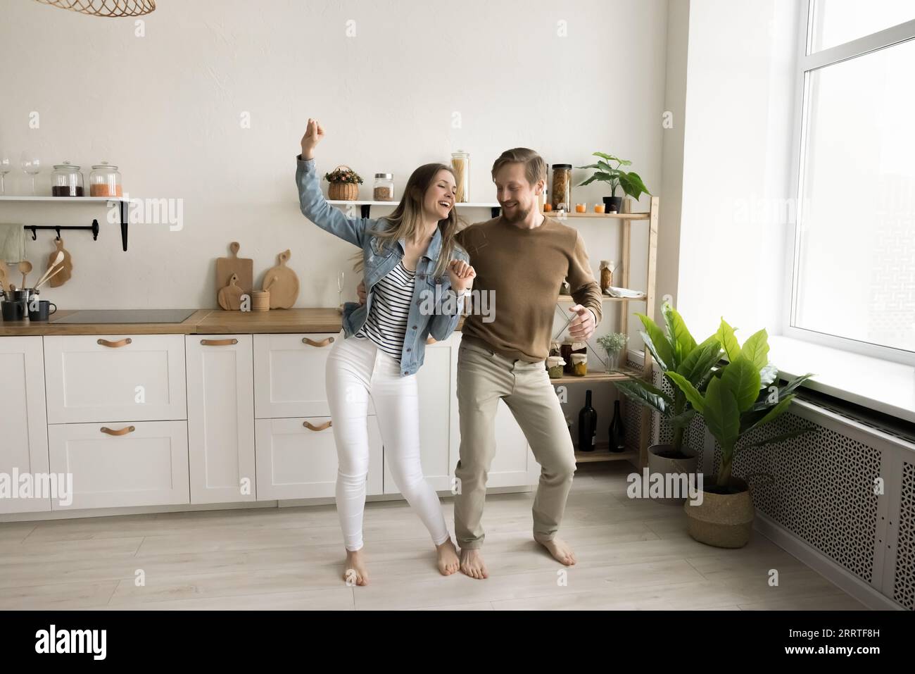 Positives aktives Paar tanzt zusammen in einer geräumigen neuen Hausküche Stockfoto