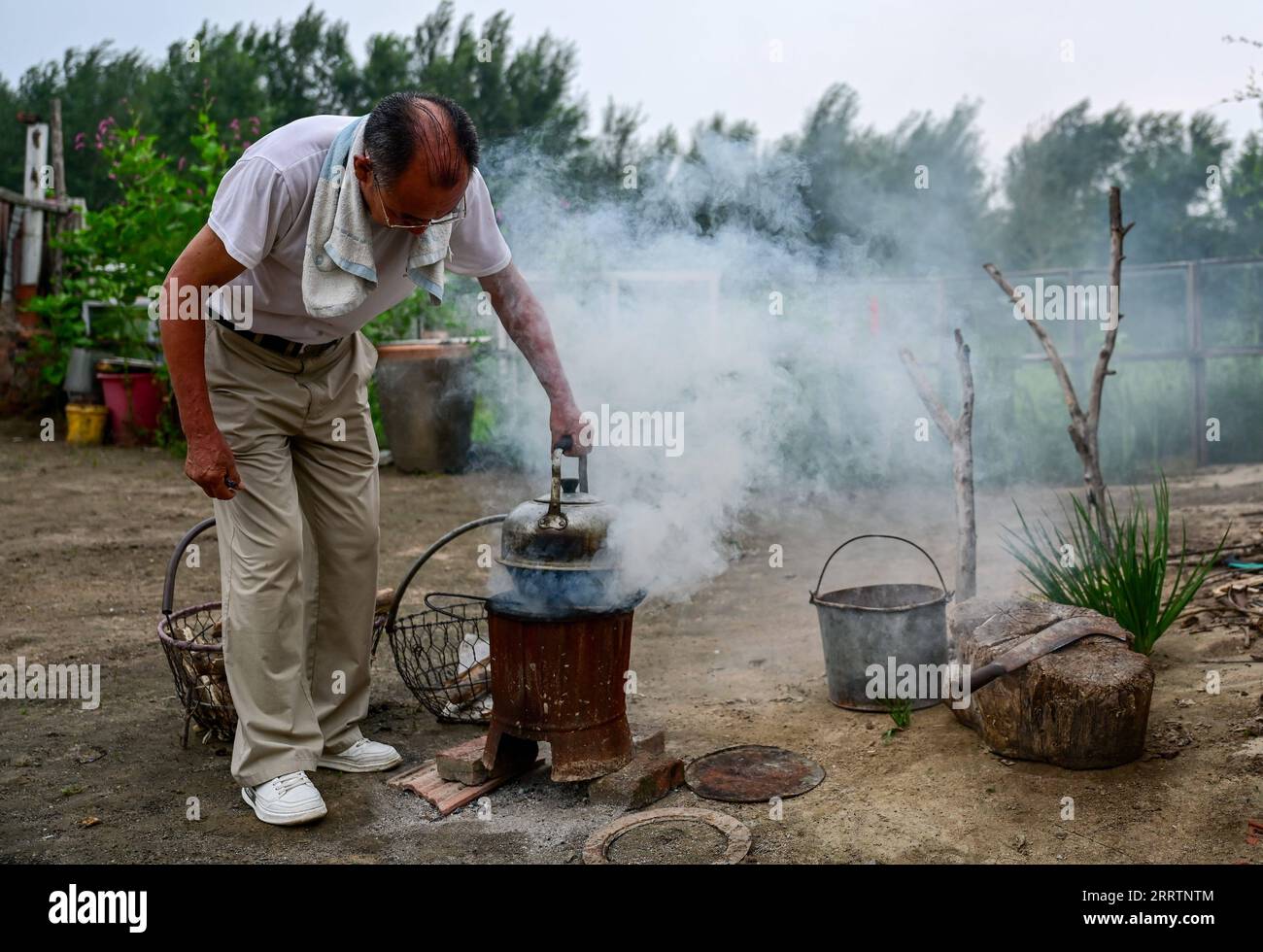 230803 -- TONGLIAO, 3. Aug. 2023 -- Bai Shun kocht Wasser in seinem Haus in Bulteger Gacha, Horqin linkes Flügel hinteres Banner der Stadt Tongliao, Nordchina Innere Mongolei Autonome Region, 2. Aug. 2023. Bulteger Gacha, ein kleines Dorf in Horqin im linken Flügel hinter dem Banner der Stadt Tongliao, befand sich im Zentrum des Horqin Sandy Landes und litt früher unter Wüstenbildung. Seit 2002 hat Bai Shun, ein ortsansässiger mongolischer Bauer, seine Familie dazu gebracht, sich in diesem Dorf zu verwurzeln und sich der Kontrolle der Wüstenbildung zu widmen. Die Überlebensrate der gepflanzten Bäume war zu Beginn aufgrund fehlender Erfahrung niedrig Stockfoto