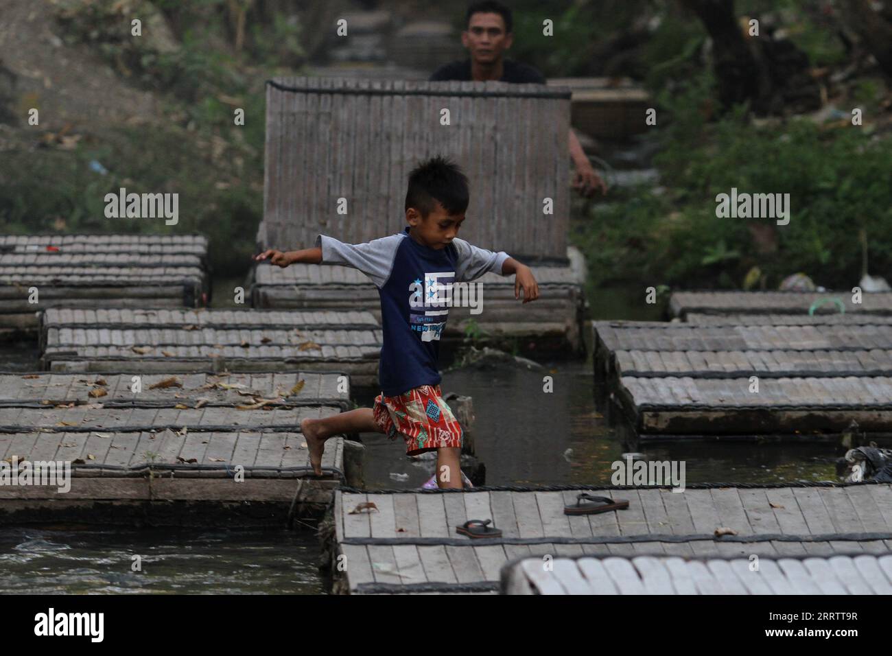 Bantul, Yogyakarta, Indonesien. September 2023. Ein Kind spielt auf Fischkäfigen im Fluss Widuri. Obwohl es die Trockenzeit ist, halten die Menschen Fische immer noch in Käfigen. Dies geschieht, weil es um den Fluss herum Wasserquellen gibt, so dass der Fluss nie austrocknet und zur Fischzucht verwendet werden kann. (Bild: © Angga Budhiyanto/ZUMA Press Wire) NUR REDAKTIONELLE VERWENDUNG! Nicht für kommerzielle ZWECKE! Stockfoto