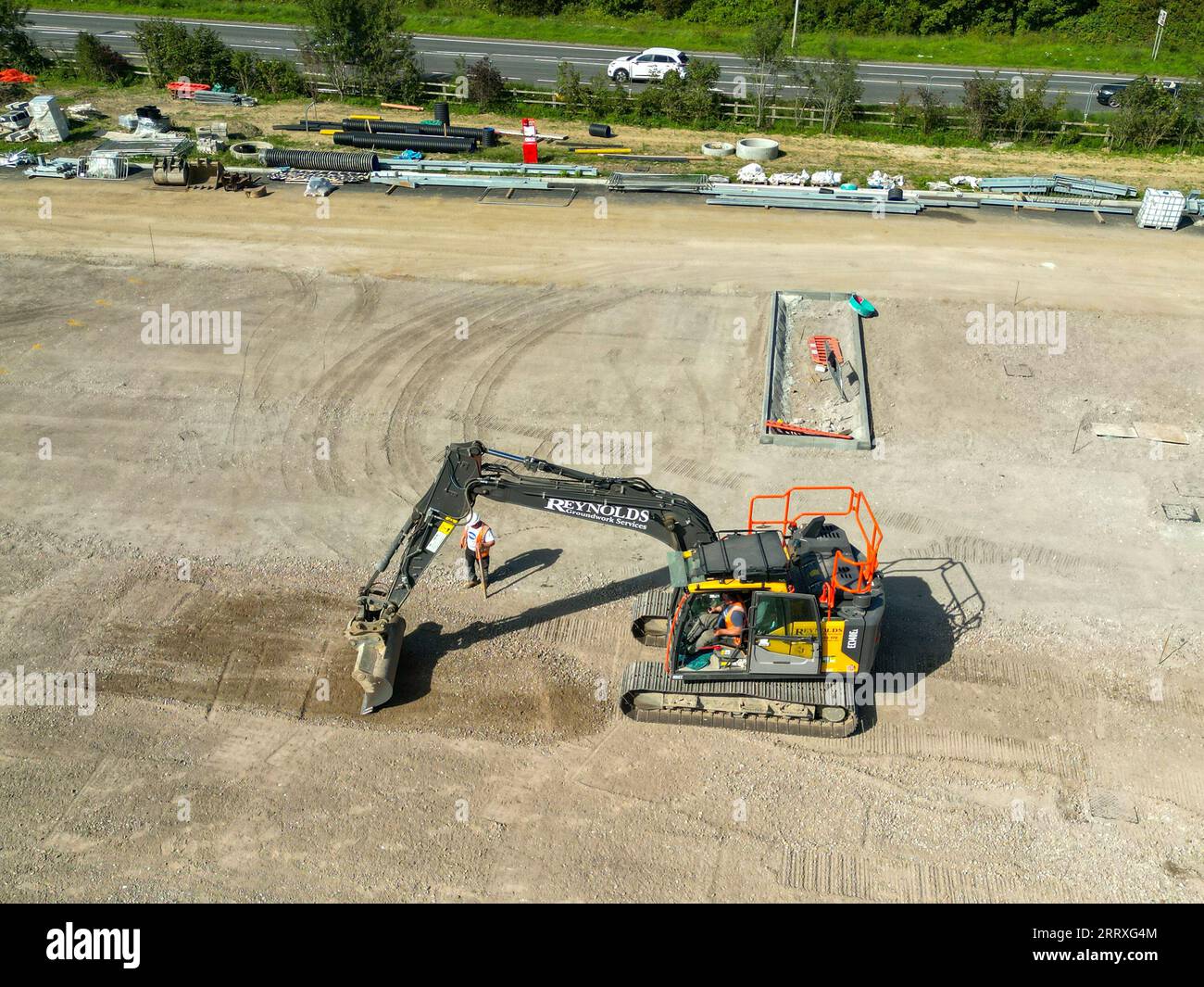 Pontyclun, Wales - 7. September 2023: Drohnen-Ansicht eines Baggers, der den Boden abkratzt, um den Parkplatz für einen neuen Supermarkt in Südwales vorzubereiten Stockfoto
