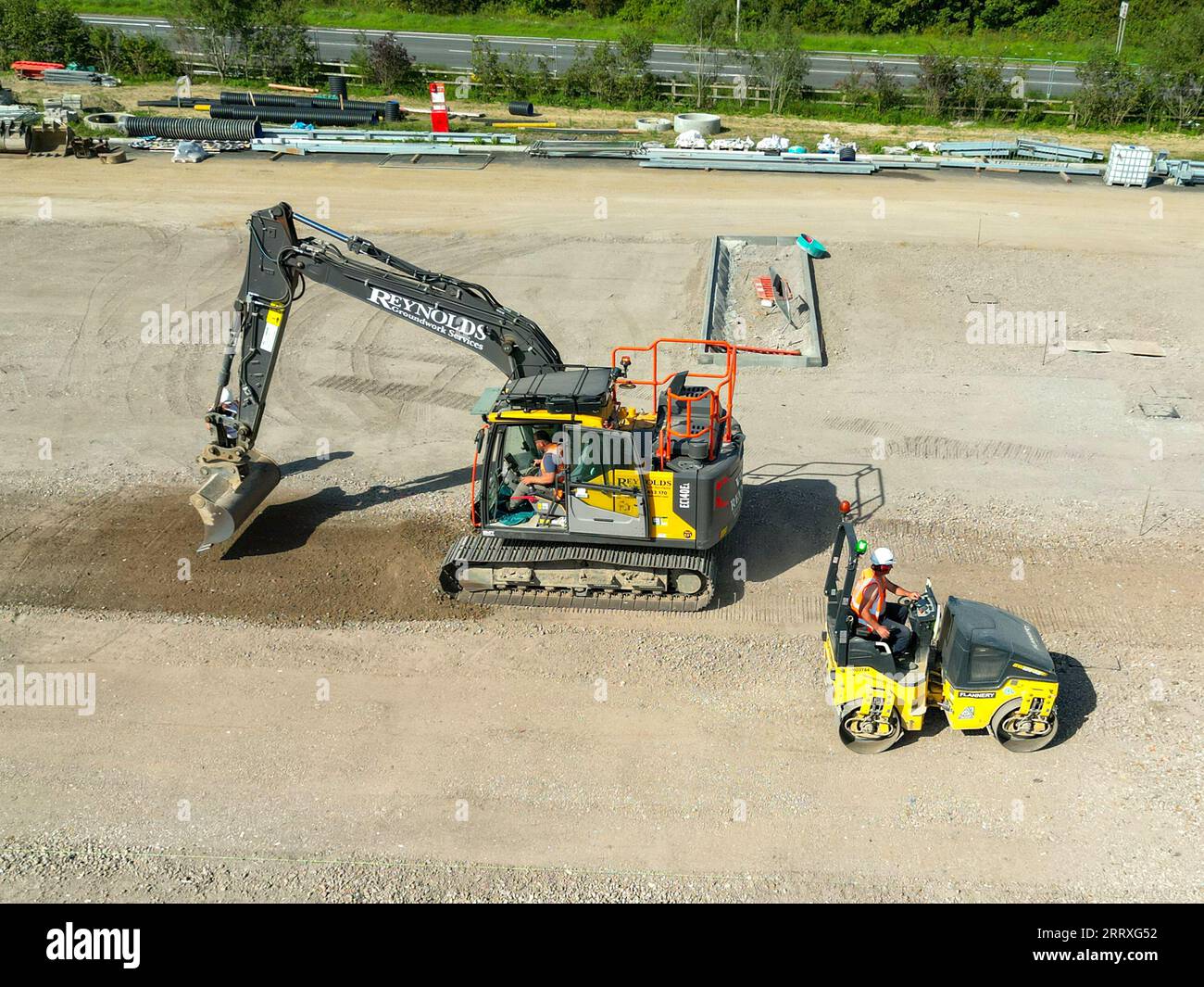 Pontyclun, Wales - 7. September 2023: Drohnenansicht eines Baggers und einer Rollermaschine, die den Parkplatz für einen neuen Supermarkt in Südwales vorbereiten Stockfoto