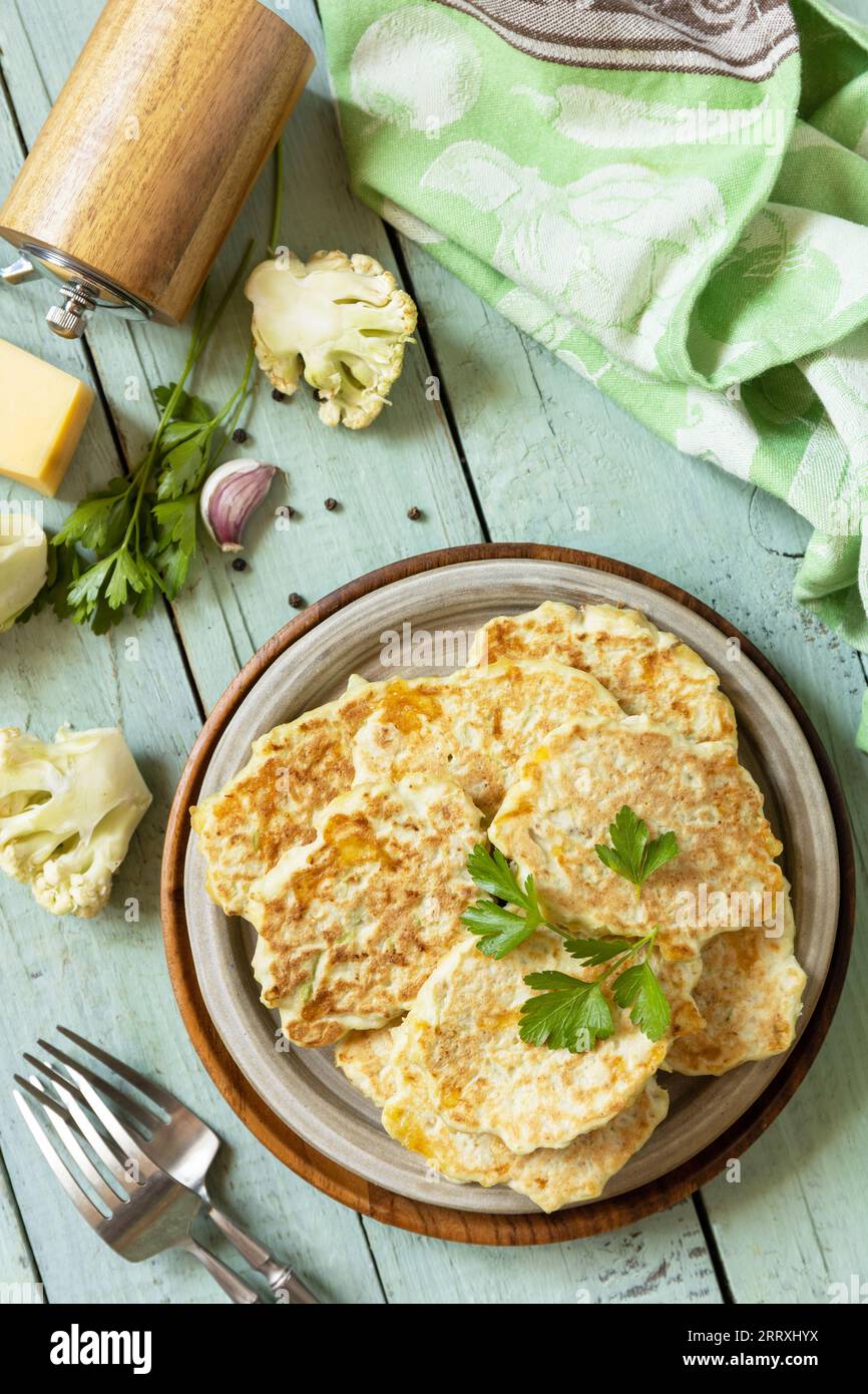 Blumenkohl-Gemüsebrühe mit Käse auf einem rustikalen Küchentisch. Gebratene vegetarische Schnitzel oder Pfannkuchen. Ansicht von oben. Stockfoto