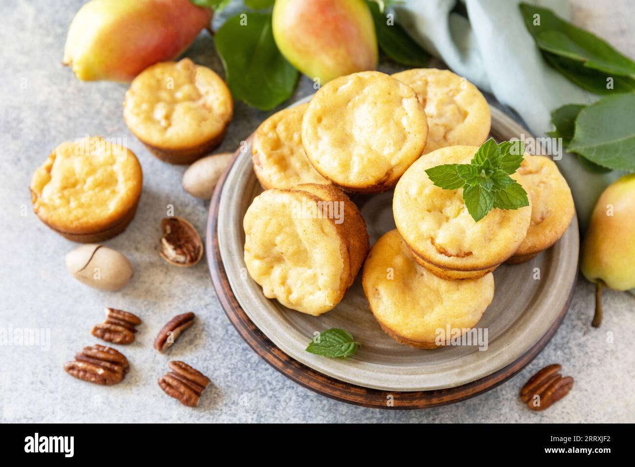 Vegetarisches Herbstbacken. Hausgemachte süße Hüttenkäse-Muffins mit Birnenfüllung, Zimt und Pekannuss auf einer Steinplatte. Stockfoto