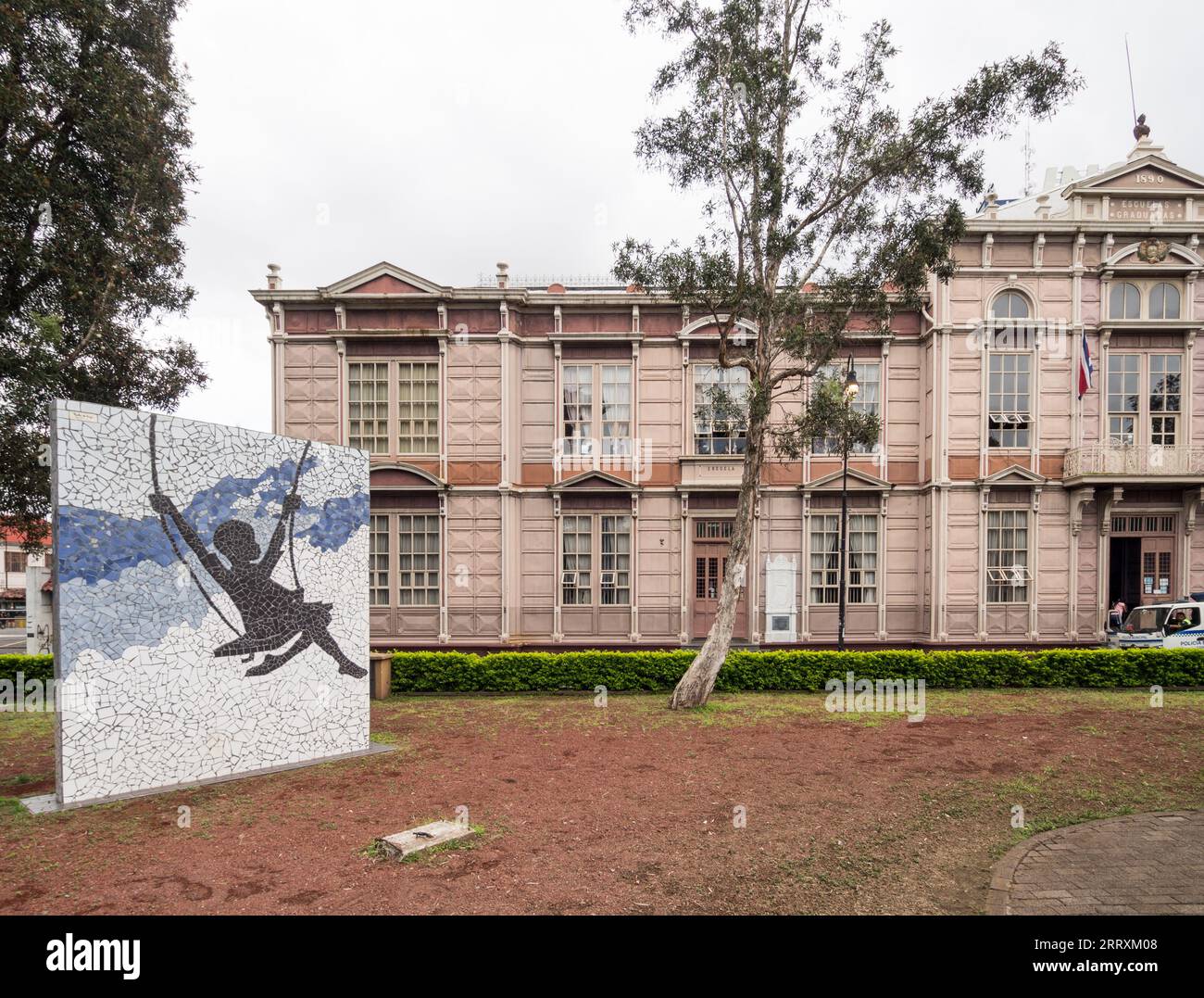 Großes Mosaikkunstwerk eines Mädchens auf einer Schaukel vor dem historischen Metallschulgebäude in San José, Costa Rica. Stockfoto