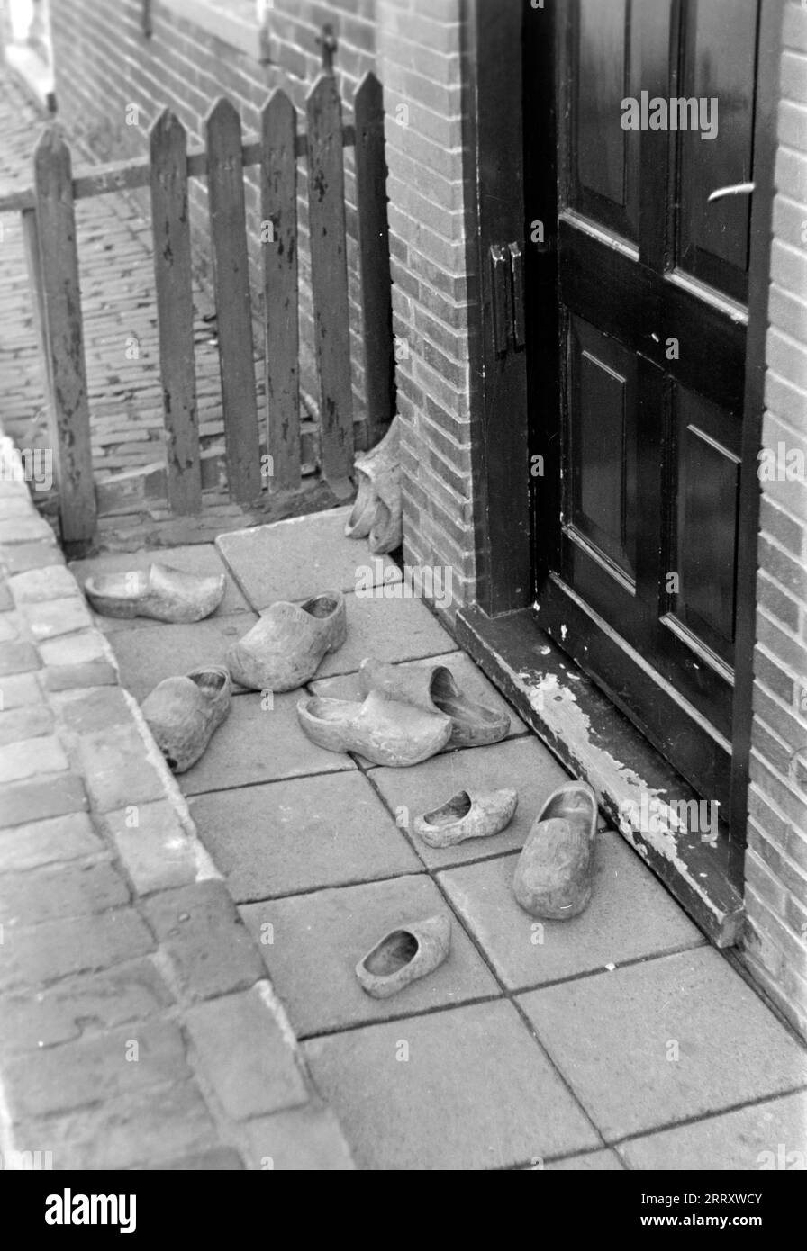 Niederländische Holzpantoffeln, genannt Klompen, liegt in einer Rinne vor der Haustür, Volendam 1941. Niederländische Hausschuhe aus Holz, genannt Klompen, liegen in einer Dachrinne vor der Eingangstür, Volendam 1941. Stockfoto