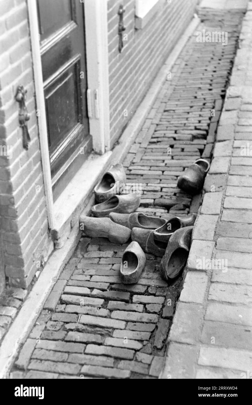 Niederländische Holzpantoffeln, genannt Klompen, liegt in einer Rinne vor der Haustür, Volendam 1941. Niederländische Hausschuhe aus Holz, genannt Klompen, liegen in einer Dachrinne vor der Eingangstür, Volendam 1941. Stockfoto