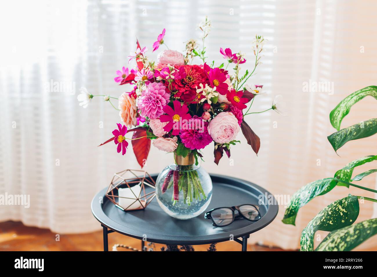 Nahaufnahme des Sommerstraußes von rosa Rosen Dahlien Blumen in Vase auf dem Kaffeetisch am Fenster. Inneneinrichtung und Einrichtung zu Hause. Leerzeichen Stockfoto