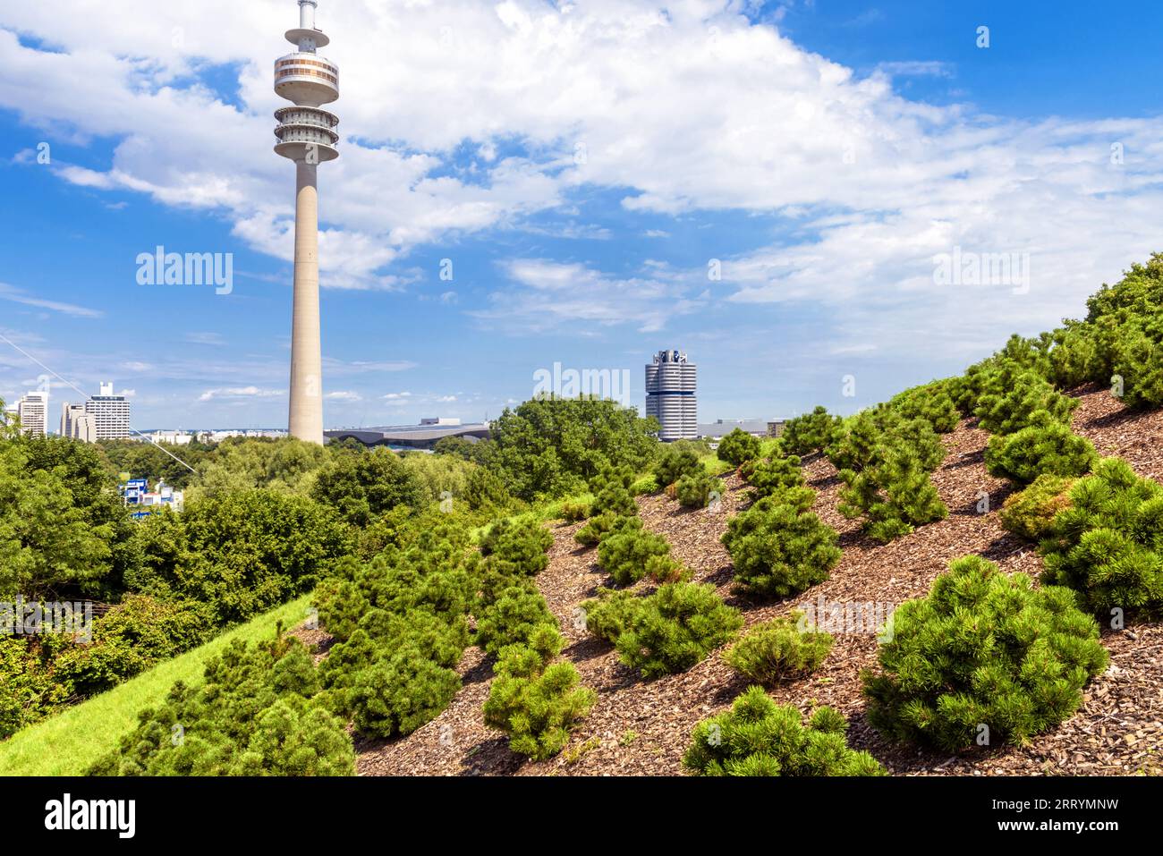 Fernsehturm und BMW Hauptsitz, Blick vom Olympiapark, München, Deutschland. Landschaft mit Wahrzeichen der Stadt Munchen auf Himmelshintergrund. Grüne Verbindung Stockfoto