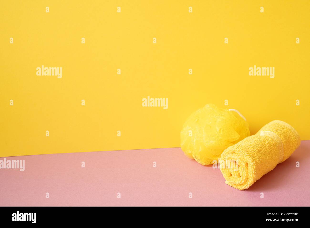 Duschkugel und Handtuch im Badezimmer auf rosafarbenem Tisch. Gelber Hintergrund. Leerzeichen kopieren Stockfoto
