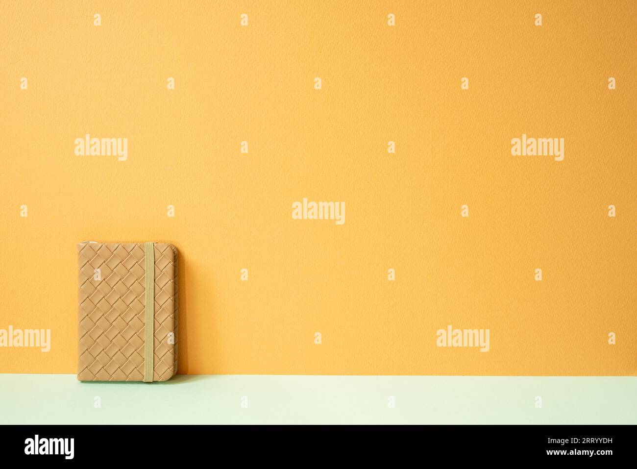 Tagebuch-Notizbuch auf minzgrünem Schreibtisch. Orangefarbener Hintergrund. Leerzeichen kopieren Stockfoto