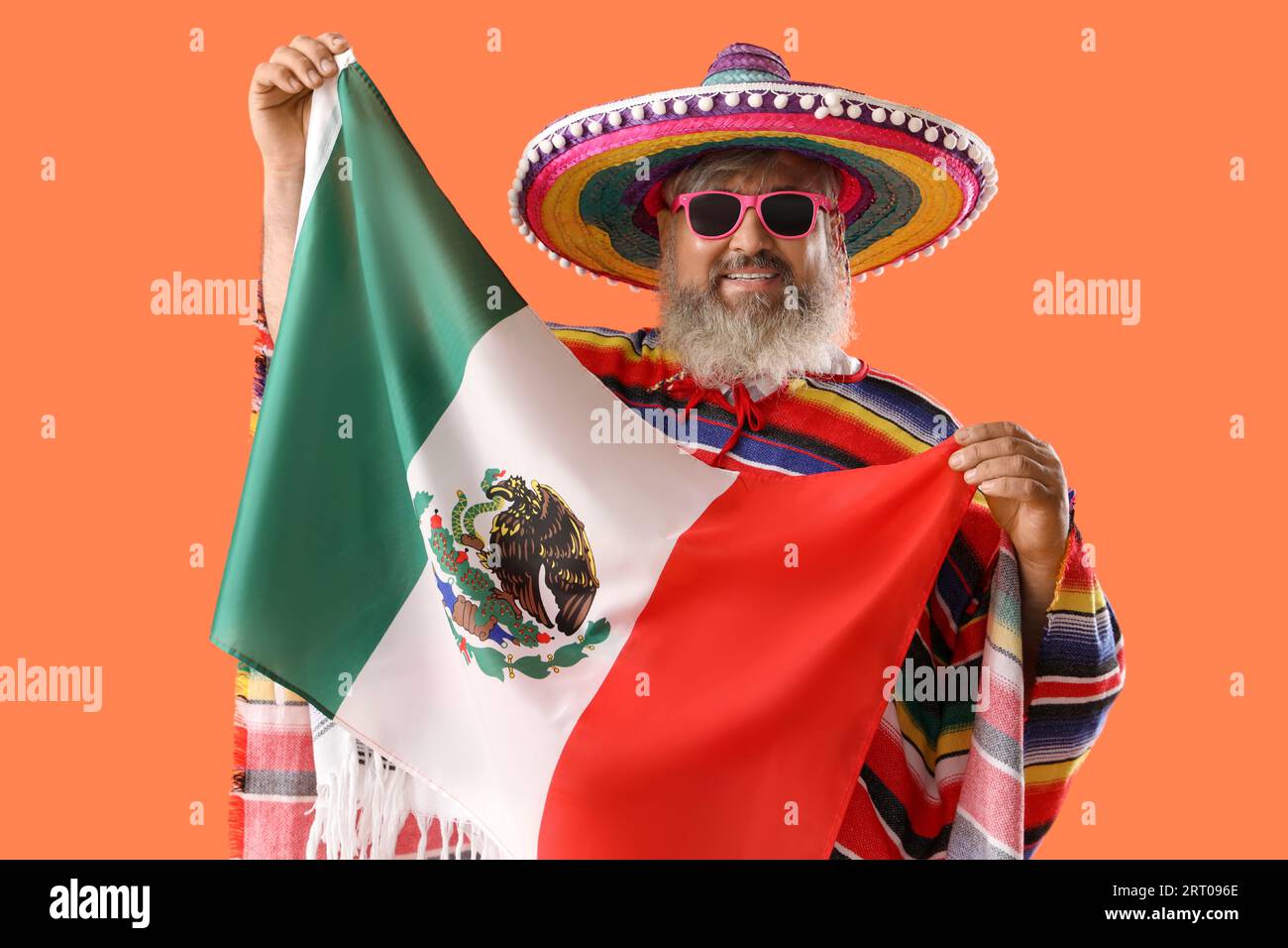 Reifer Mann in Sombrero-Hut mit mexikanischer Flagge auf orangem Hintergrund Stockfoto