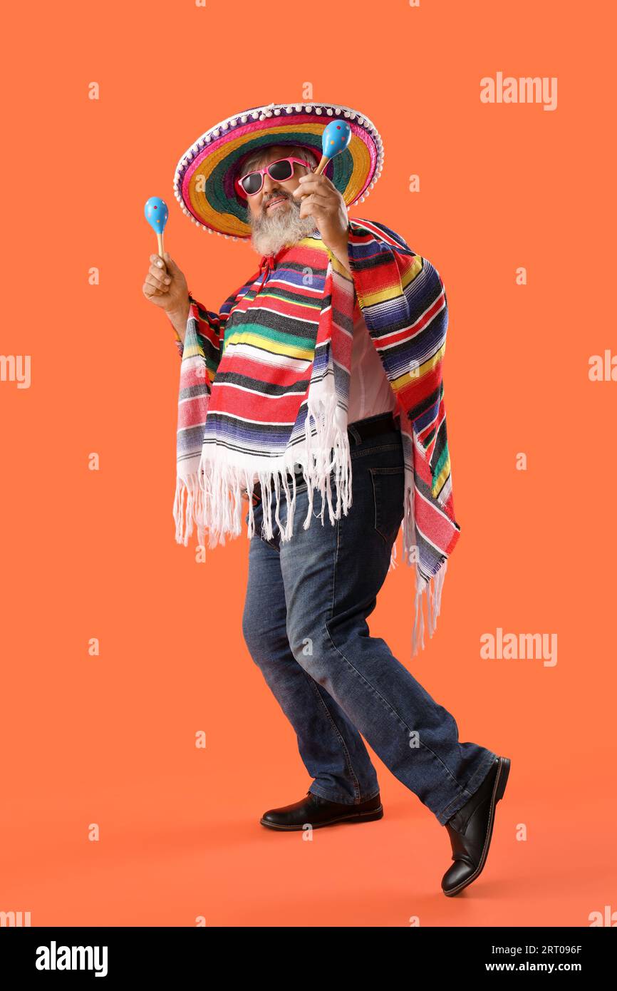 Reifer Mann im Sombrero-Hut mit Maracas auf orangem Hintergrund. Mexikos Unabhängigkeitstag Stockfoto