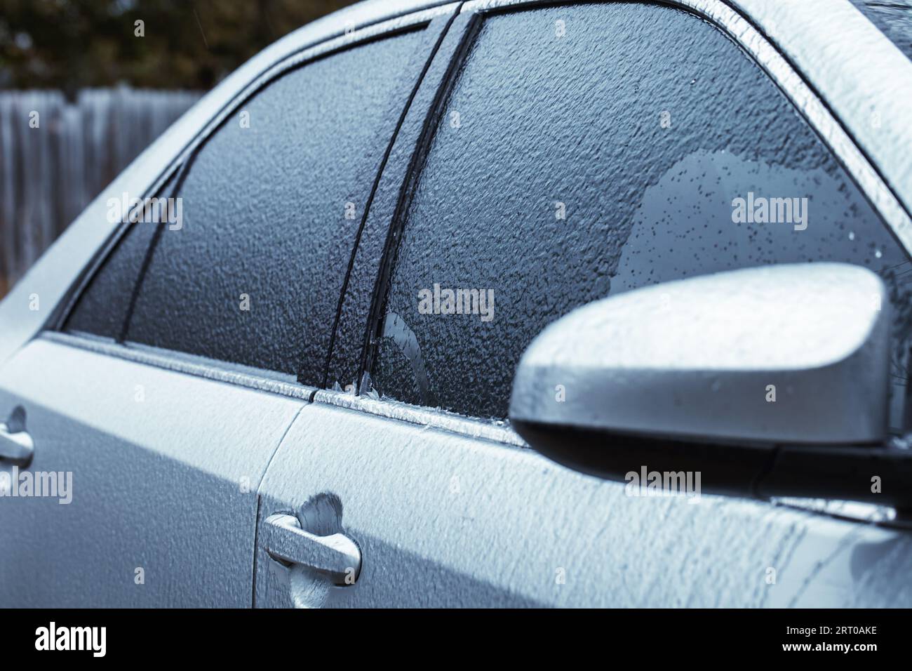Detail des Autos, das nach einem Eissturm mit Graupel oder Glasur bedeckt ist. Pendlerprobleme im Winter Stockfoto