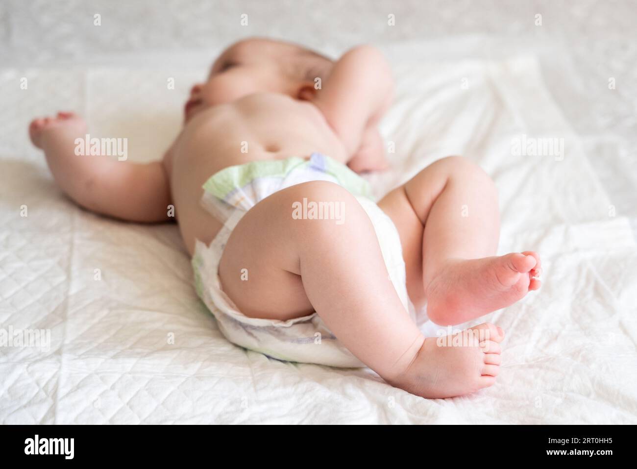 Diaperierte Säuglingsliege mit Füssen im Fokus. Das Konzept der Wertschätzung kleiner Momente im Leben Stockfoto