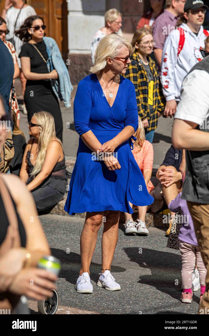 Frau mittleren Alters mit blauem Kleid, die an einem sonnigen Sommertag in Helsinki, Finnland, in der Menge steht Stockfoto