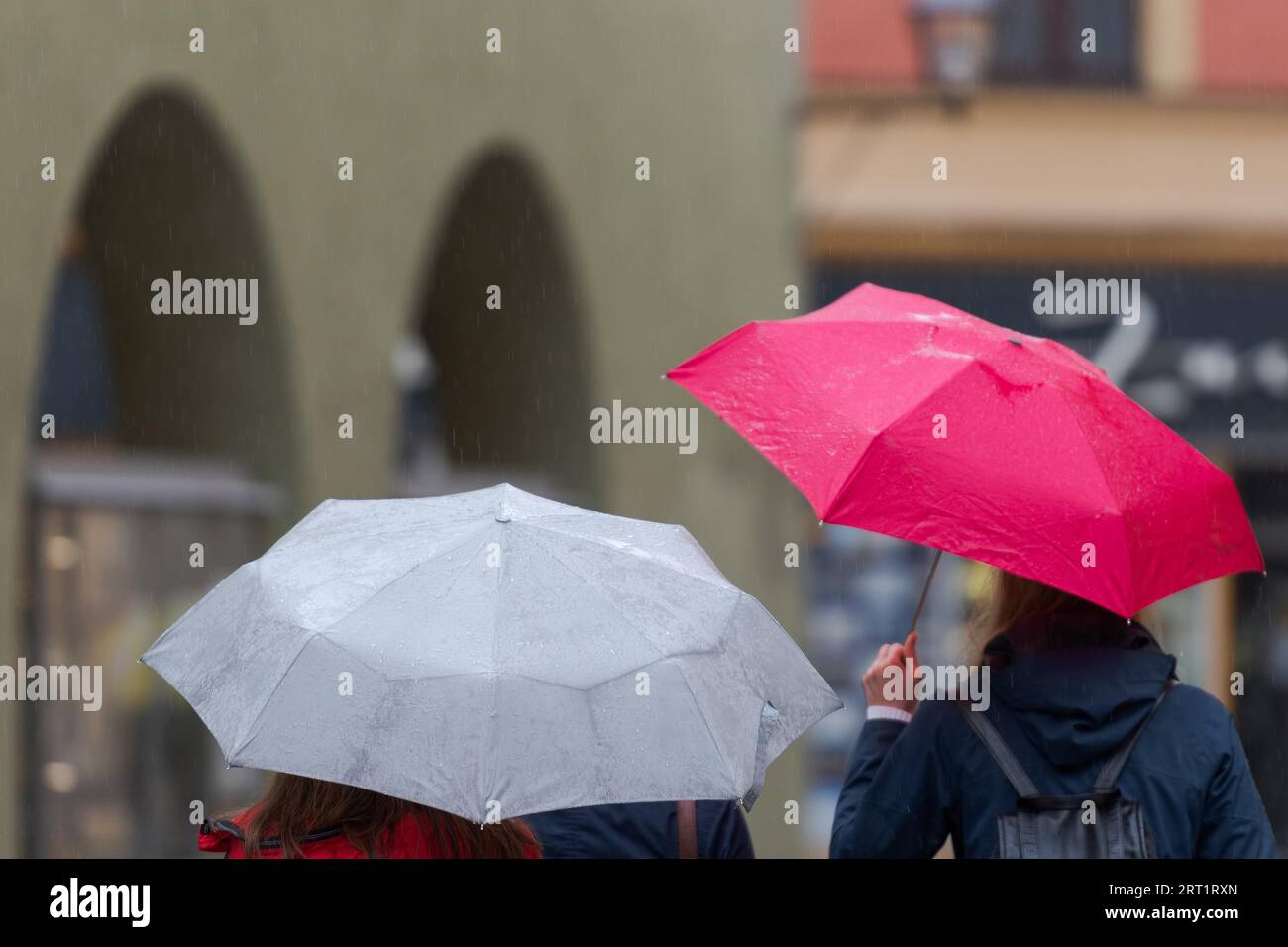Oberkörper von zwei nicht erkennbaren Menschen mit Regenschirmen, die durch die Straße in alten engen Schuppungsstraße an regnerischen Tag gehen Stockfoto
