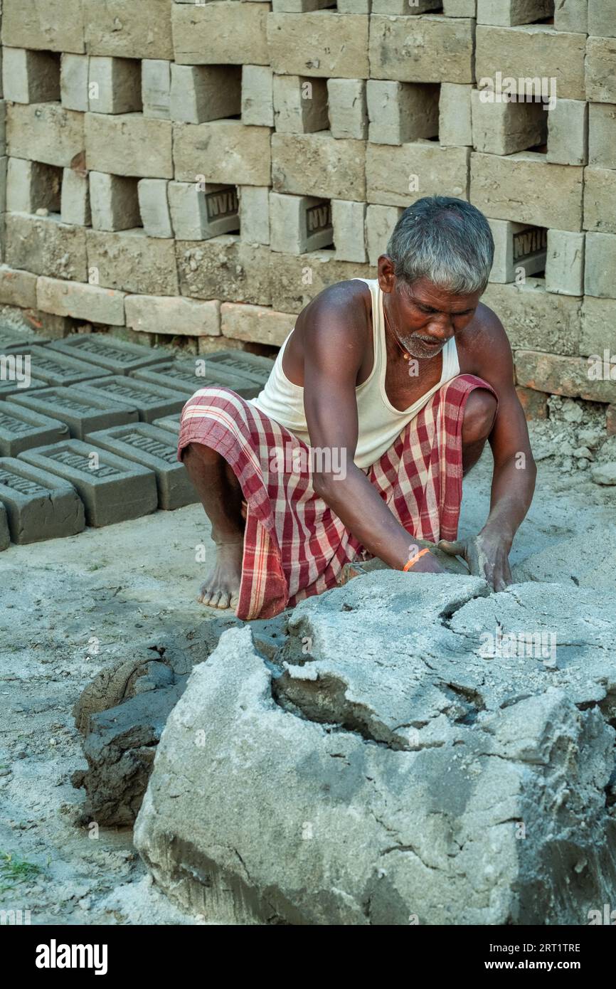 In West-Bengalen, Indien, bereitet ein Gelegenheitsarbeiter fleißig Boden für die traditionelle Ziegelsteinproduktion vor und verkörpert das reiche Erbe und Handwerk der Region Stockfoto
