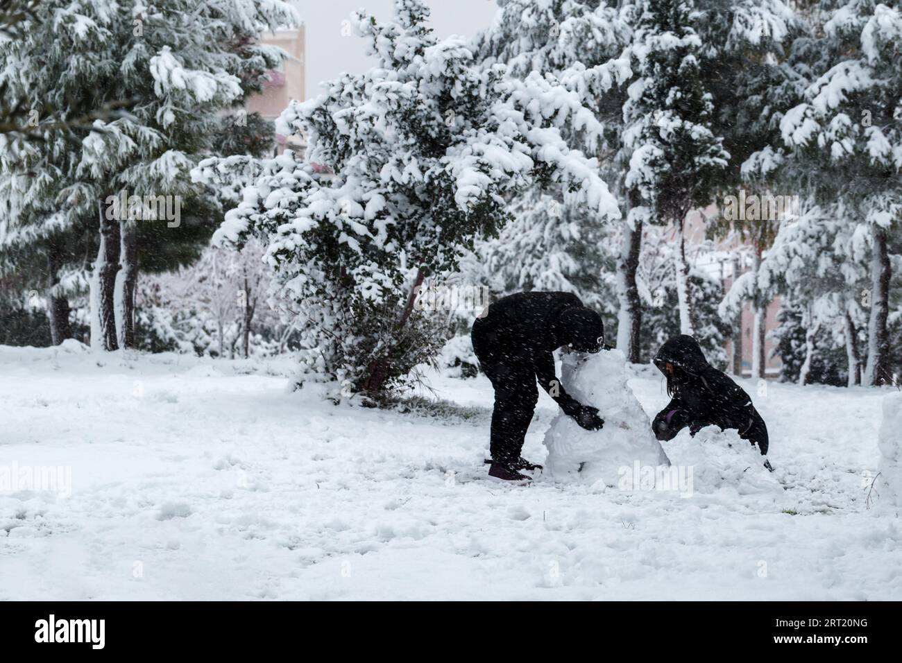 Ein Paar, das einen Schneemann macht, ungewöhnliches Wetter in Athen, Griechenland Stockfoto