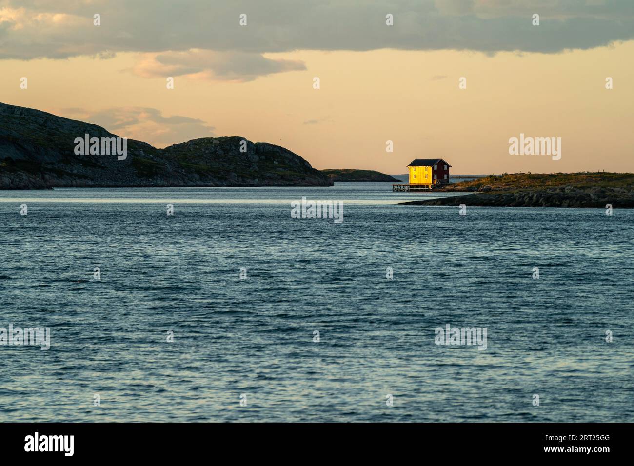 Ein einsames rotes Haus im Licht der untergehenden Sonne an der Westküste von Vega, Norwegen Stockfoto