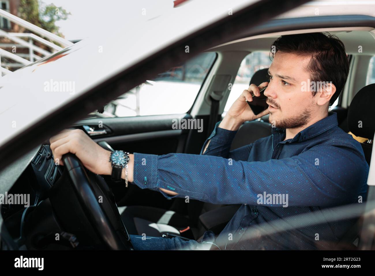 Junger Mann, der in seinem Auto telefoniert Stockfoto
