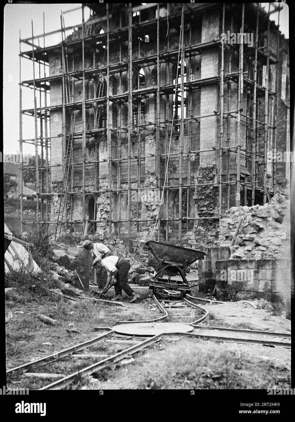Rievaulx Abbey, Rievaulx, Ryedale, North Yorkshire, 1924-1929. Das Refektorium in der Rievaulx Abbey wird restauriert, mit Gerüsten rund um das Gelände, einer temporären Eisenbahn für den Transport von Baumaterial und Schutt und zwei Männern, die im Vordergrund arbeiten. Die Sanierung und Räumung des Geländes erfolgte in den 1920er Jahren Stockfoto
