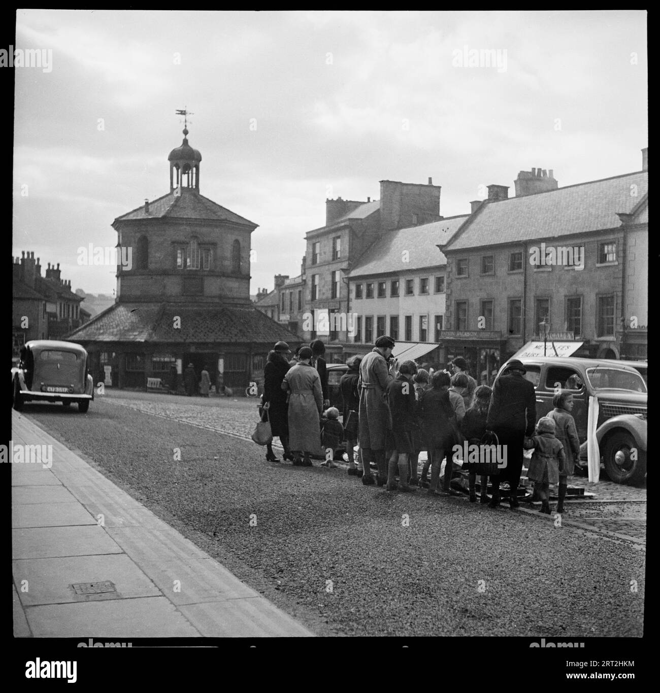 Market Place, Barnard Castle, County Durham, 1936. Blick nach Süden entlang des Marktplatzes in Richtung des Markkreuzes in Barnard Castle, wobei eine Gruppe von Menschen im Vordergrund zu sehen ist. Stockfoto