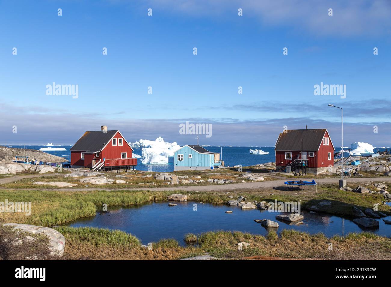 Qeqertarsuaq, Grönland, 05. Juli 2018: Bunte Holzhäuser mit Eisbergen im Hintergrund Stockfoto