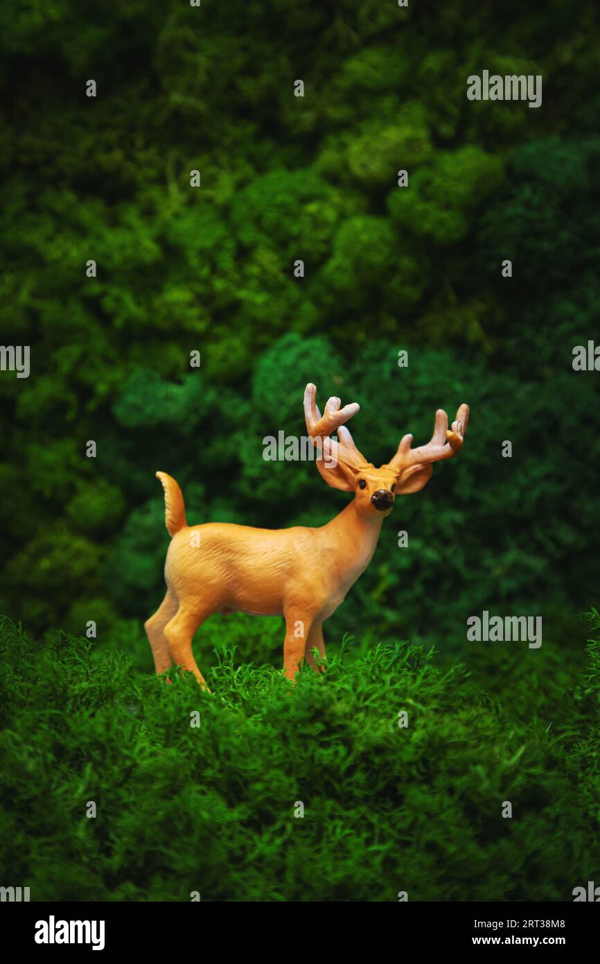 Miniaturfigur eines Hirsches auf natürlichem Hintergrund. Welttiertag, Erdtag, Konzept. Stockfoto