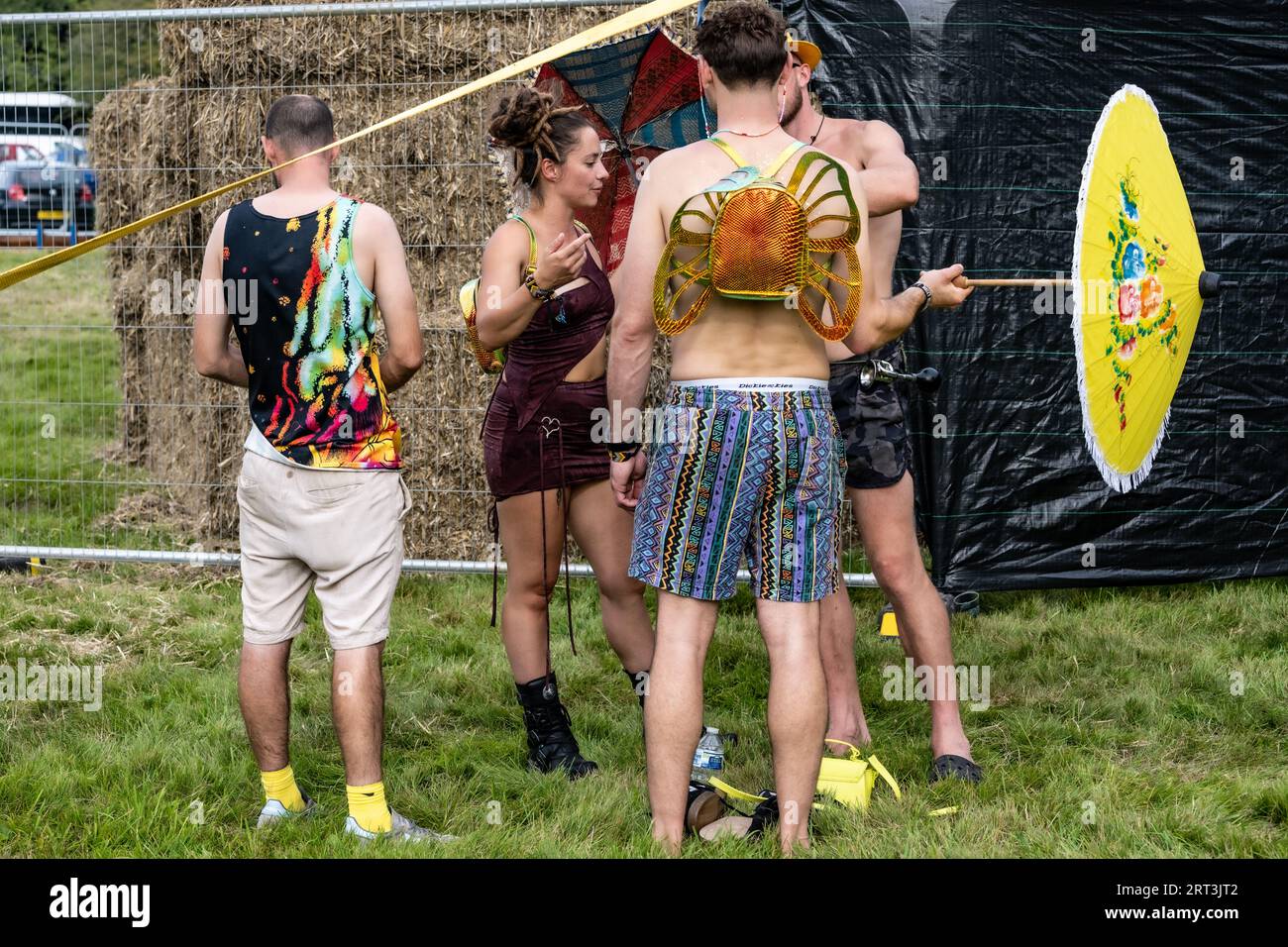 Schicker Sonnenschirm und ein Schmetterlings-Rucksack. Musikfestival. Mucky Weekender Festival, Vicarage Farm, Woodmancott, in der Nähe von Winchester, Hampshire, UK Stockfoto