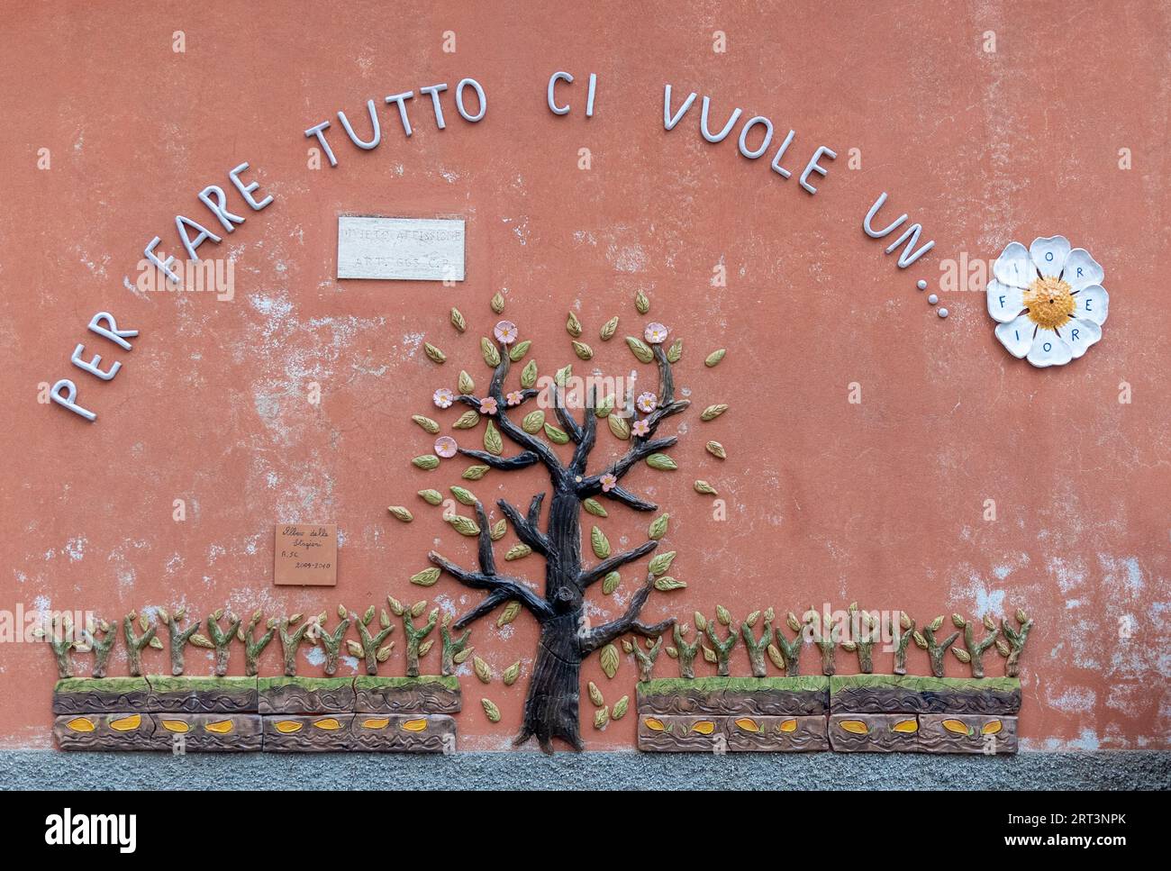 Detail einer keramischen Wanddekoration an der Fassade eines Kindergartens mit dem Text: "Alles machen, was es braucht, eine Blume", Savona, Ligurien, Italien Stockfoto