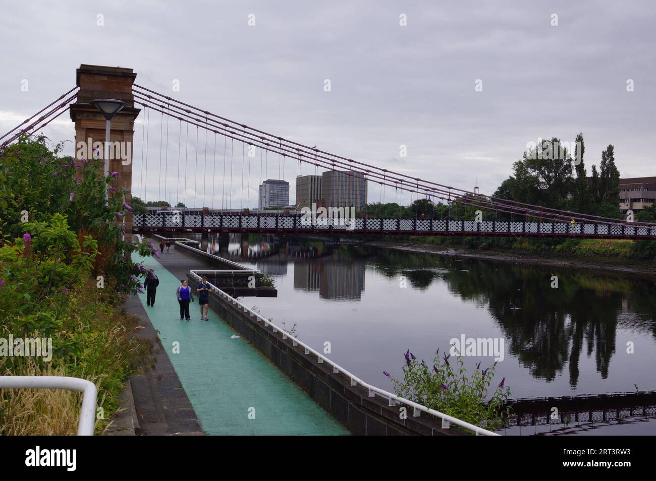 Glasgow, Schottland (UK): Menschen, die am Nordufer des Flusses Clyde unter der Hängebrücke South Portland Street spazieren Stockfoto