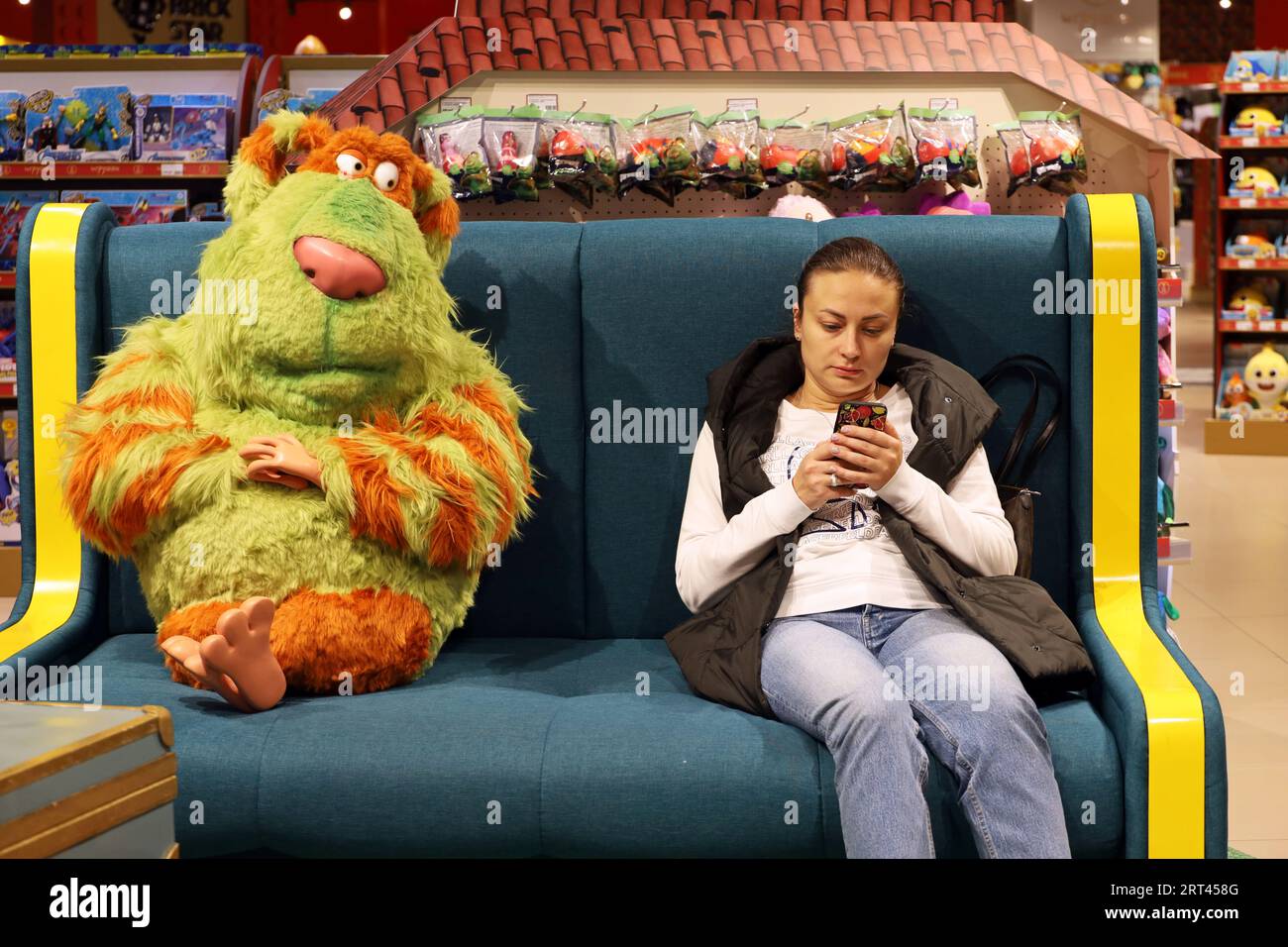 Frau sitzt mit Smartphone im Spielwarenladen Stockfoto