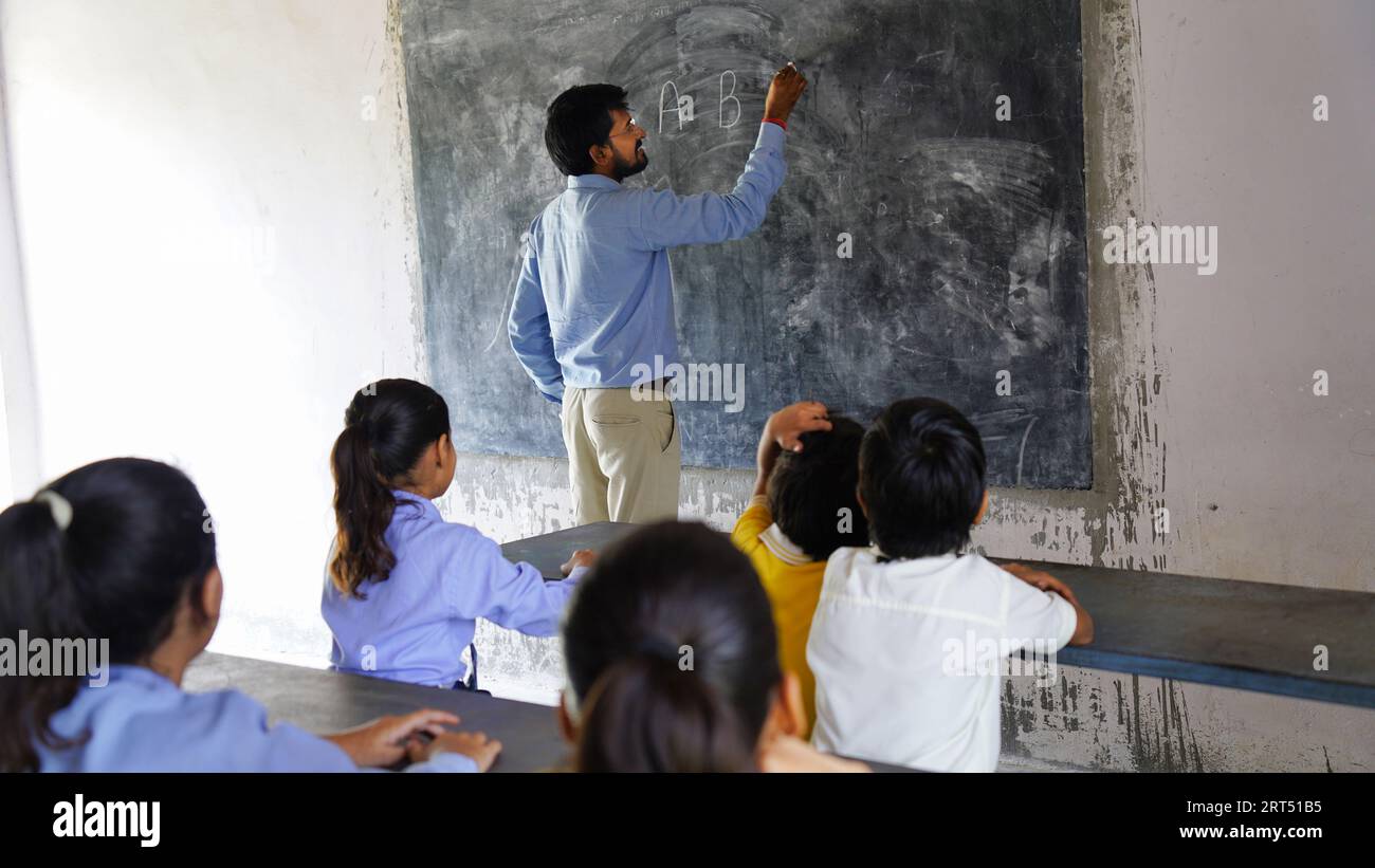 Indischer Lehrer unterrichtet ländliche Schüler im Klassenzimmer, typische Szene in einer ländlichen oder kleinen Dorfschule in Indien Stockfoto