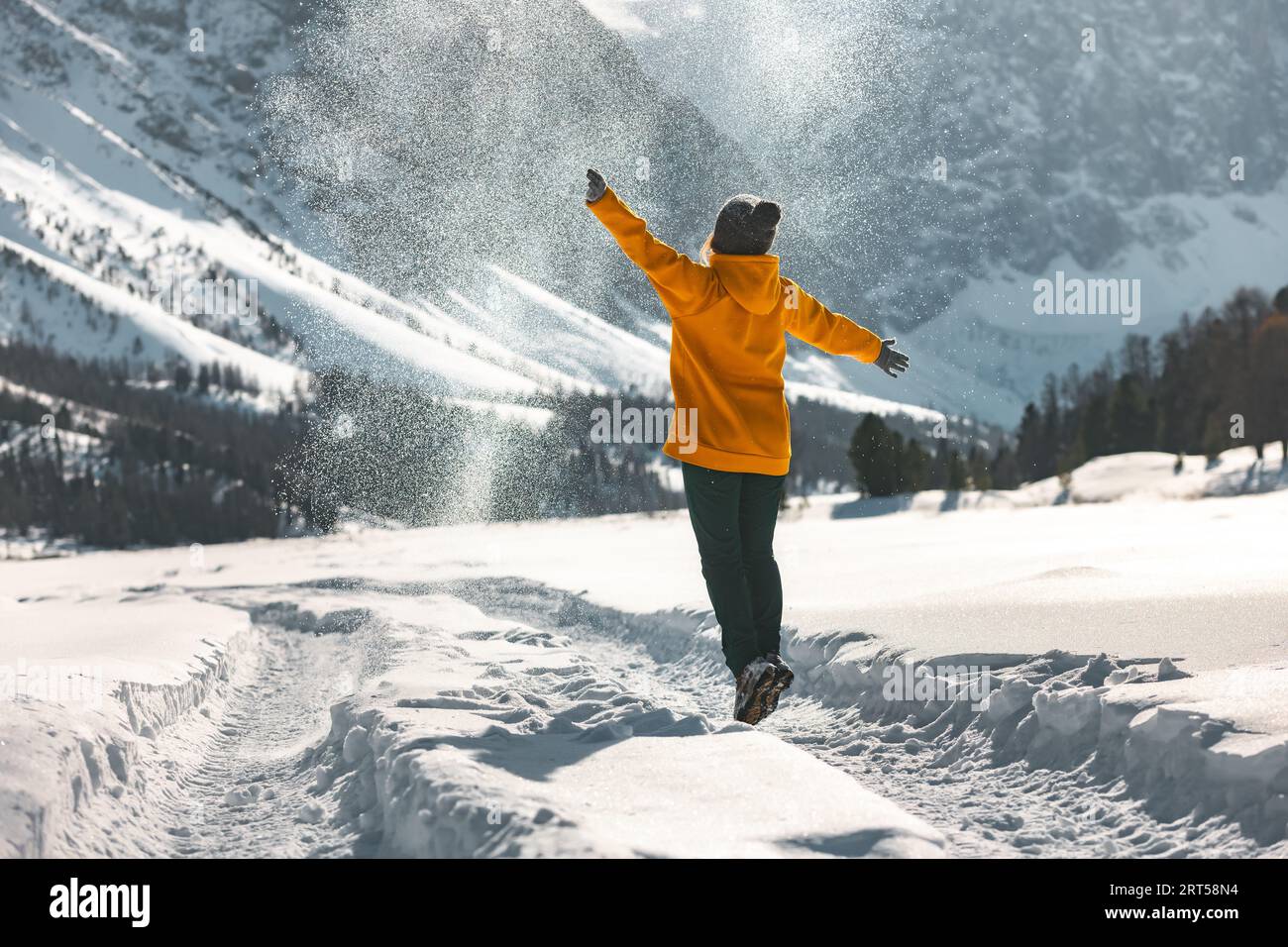 Glückliche junge Frau oder Mädchen springt und wirft Pulverschnee in die Berge. Winterurlaub-Konzept Stockfoto