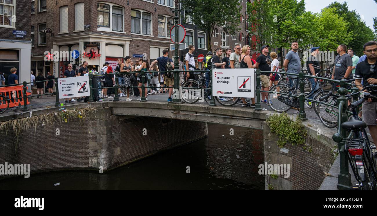 Amsterdam, Niederlande - 17. Juni 2023: Menschenmassen am frühen Abend im Rotlichtviertel von Amsterdam und Schilder über das Trinken und Rauchen von Cannabis in Stockfoto